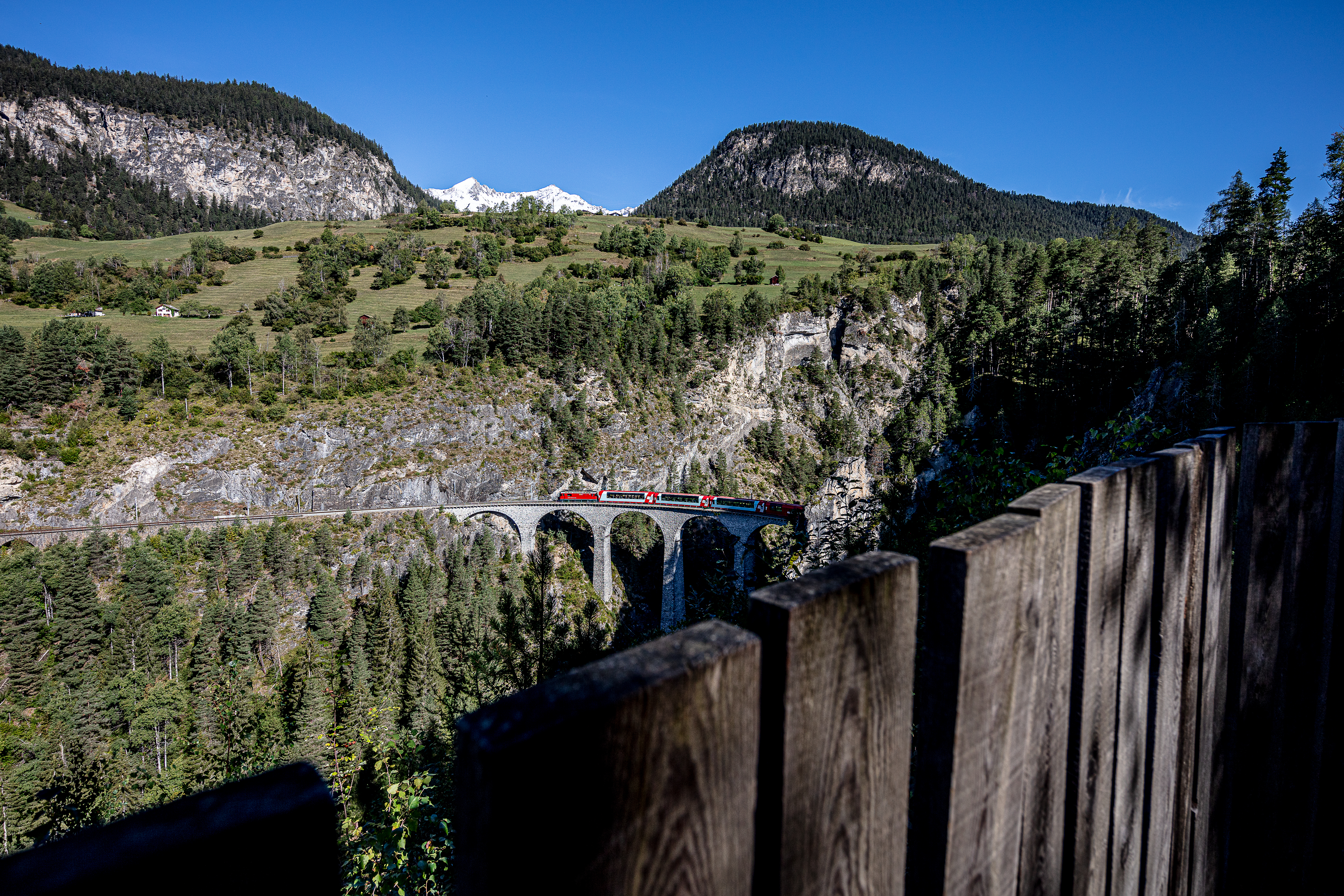 Die Aussichtsplattform Acatos mit Blick auf einen vorbeifahrenden Zug und das Landwasserviadukt