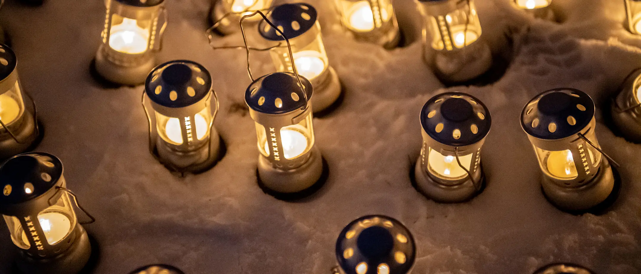 Lanterns with candles glow in the snow.