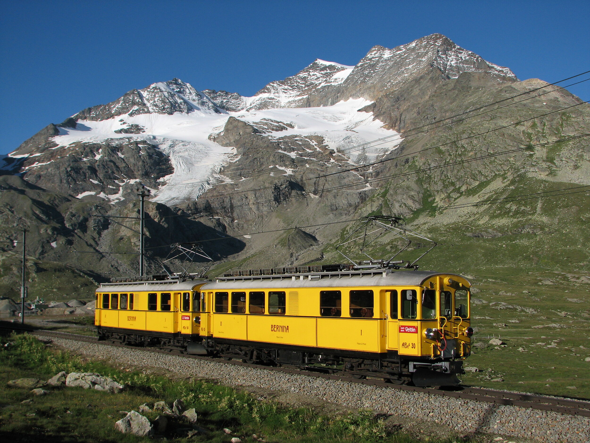Zwei gelbe Triebwagen der alten Berninabahn sind auf der Berninalinie unterwegs. 