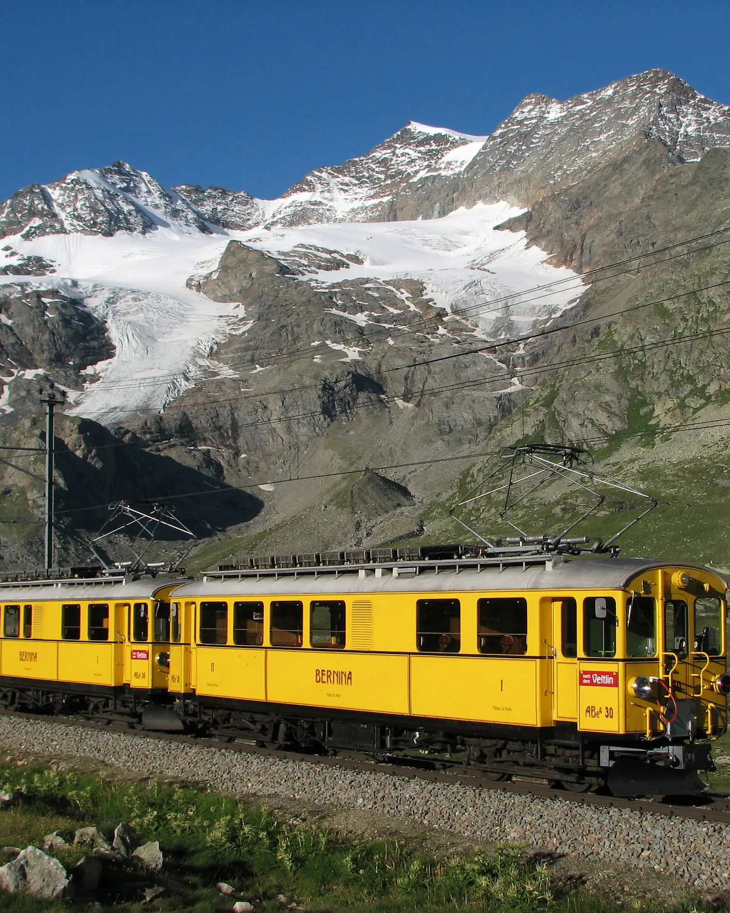 Zwei gelbe Triebwagen der alten Berninabahn sind auf der Berninalinie unterwegs.