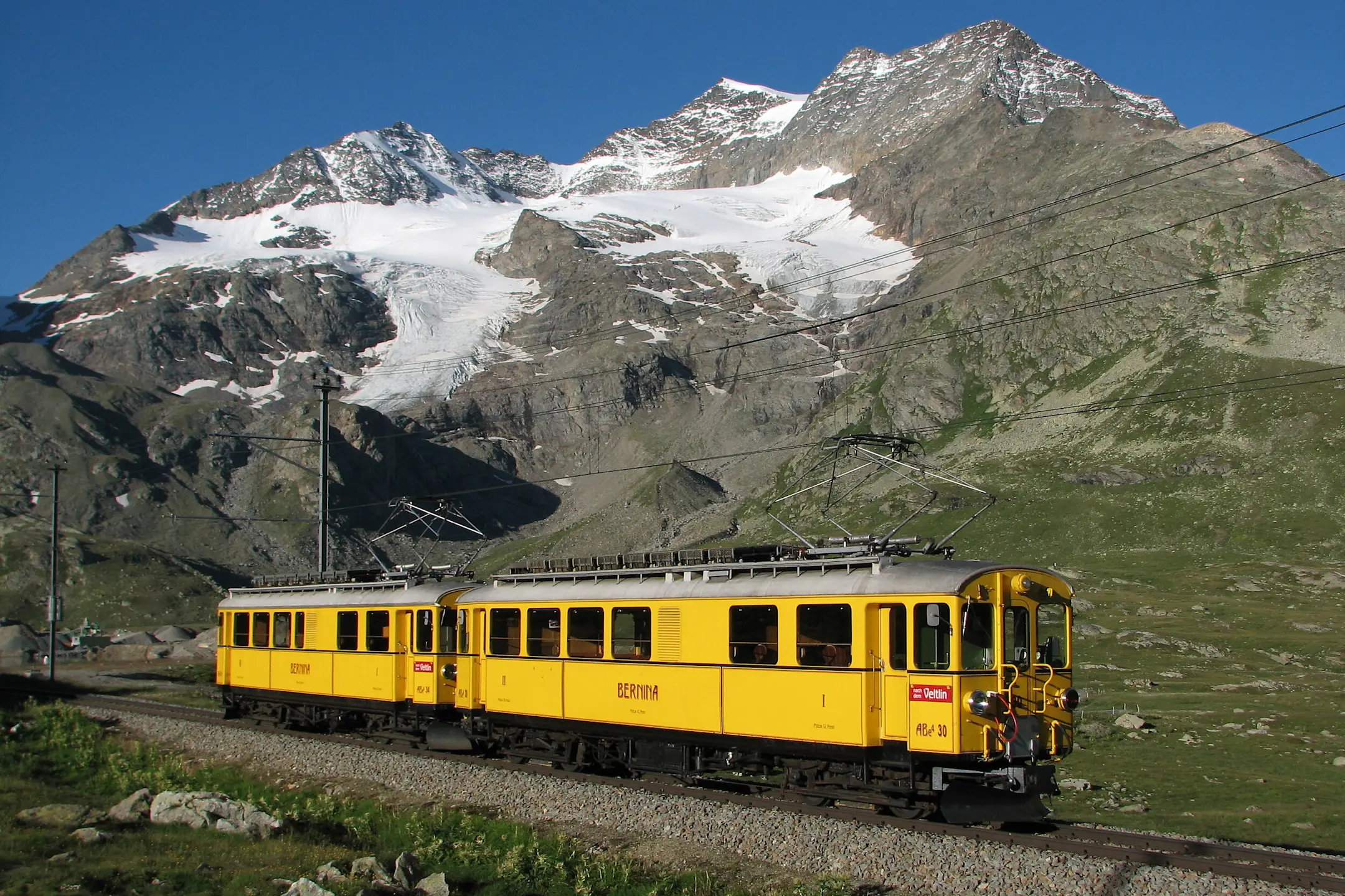 Zwei gelbe Triebwagen der alten Berninabahn sind auf der Berninalinie unterwegs.