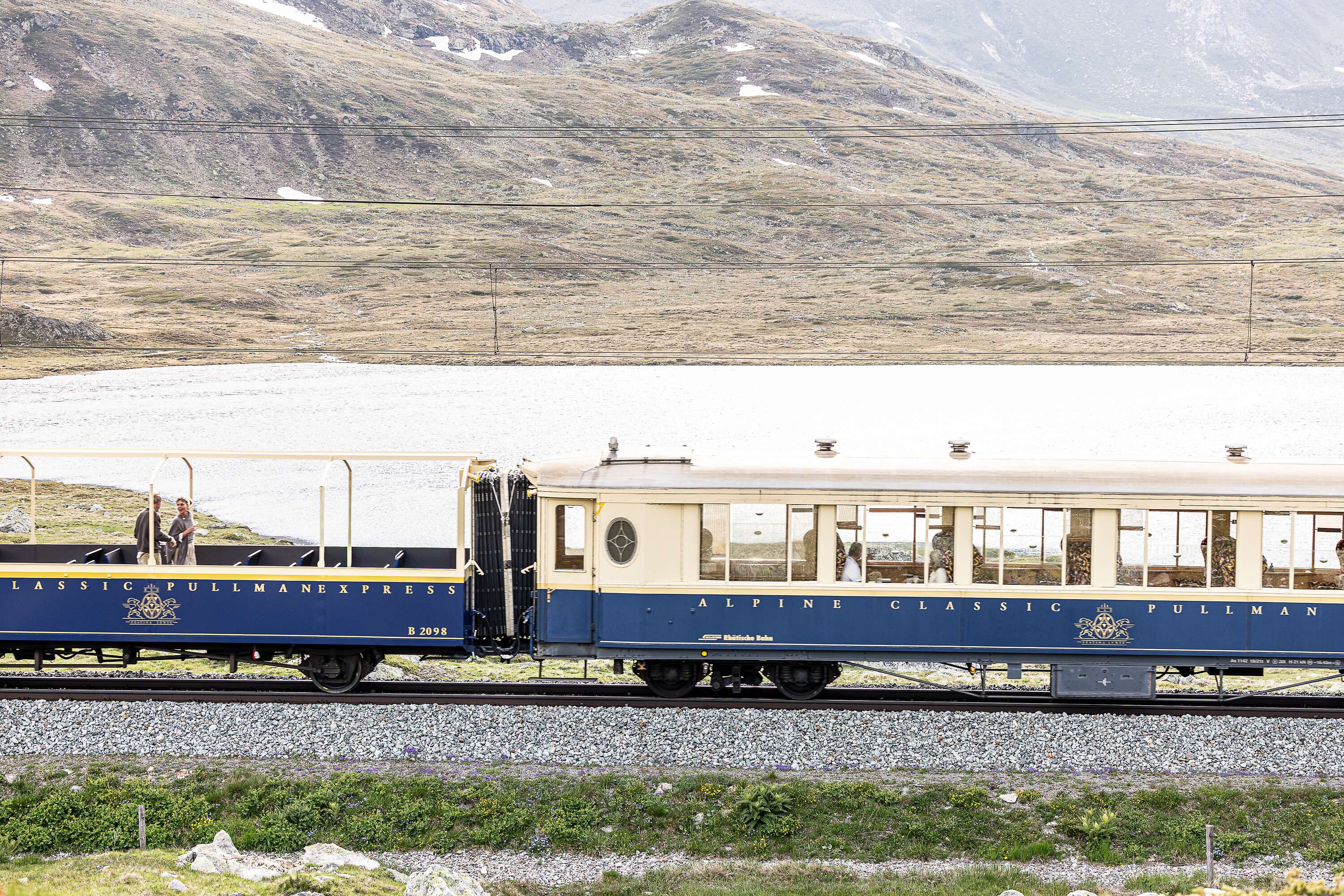 Ein Pullman Class Wagen des Bernina Express fährt durch die alpine Landschaft am Lago Bianco.
