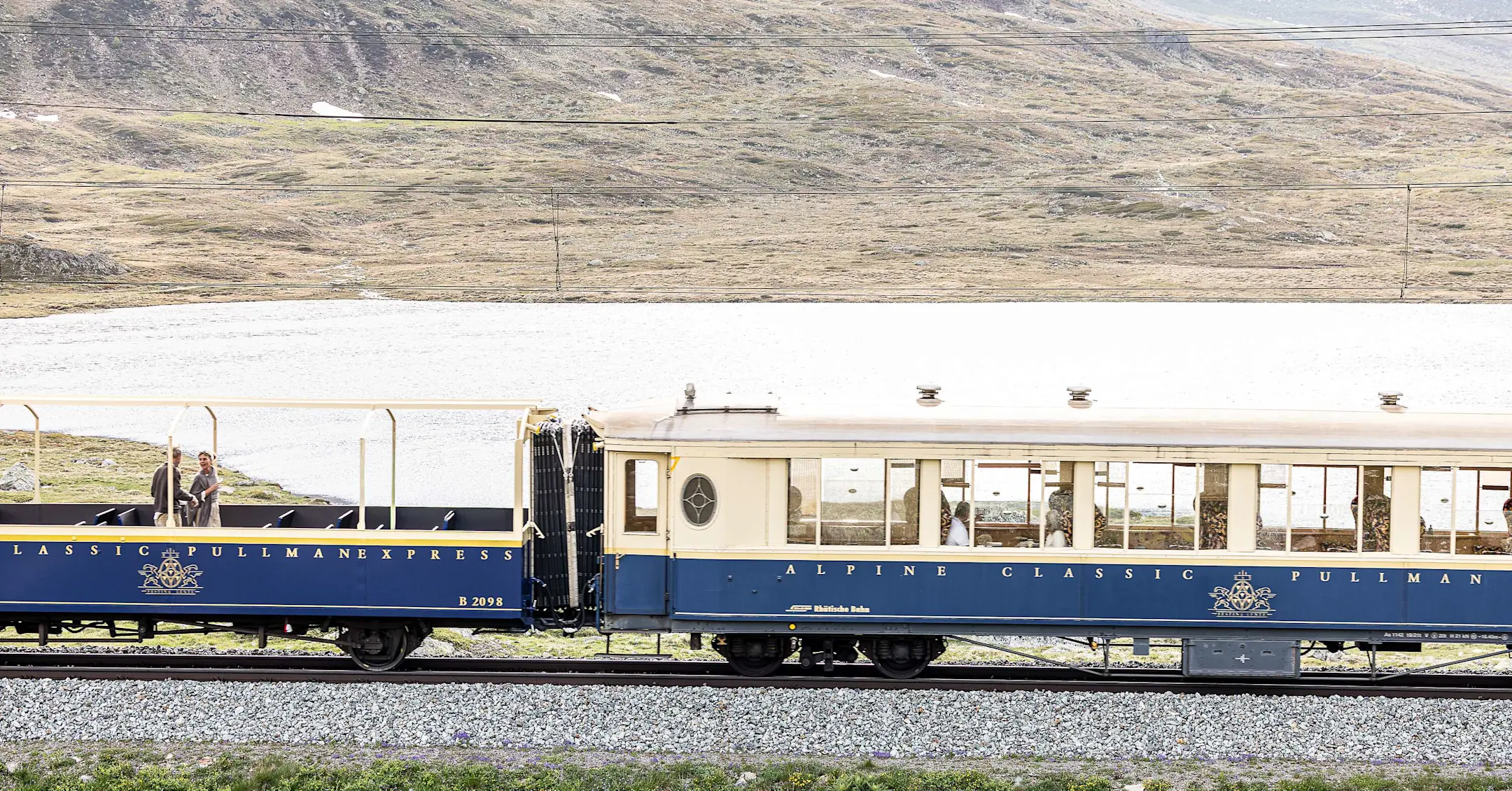 Ein Pullman Class Wagen des Bernina Express fährt durch die alpine Landschaft am Lago Bianco.