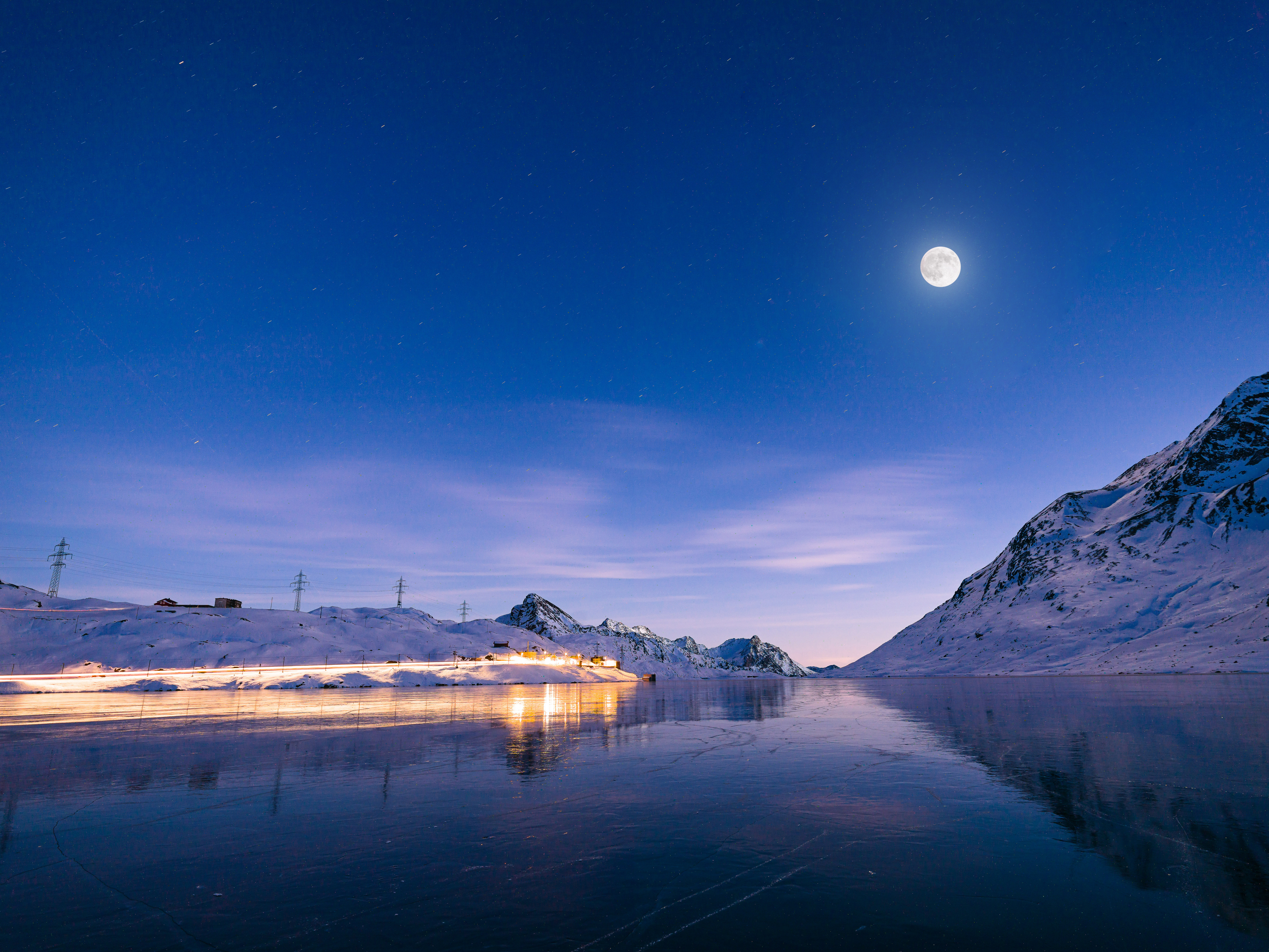 Vollmond am Lago Bianco, Bild in der Nacht, hell beleuchtete Bahnstrecke.