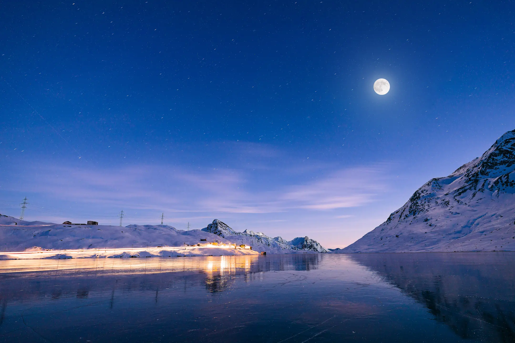 Vollmond am Lago Bianco, Bild in der Nacht, hell beleuchtete Bahnstrecke.