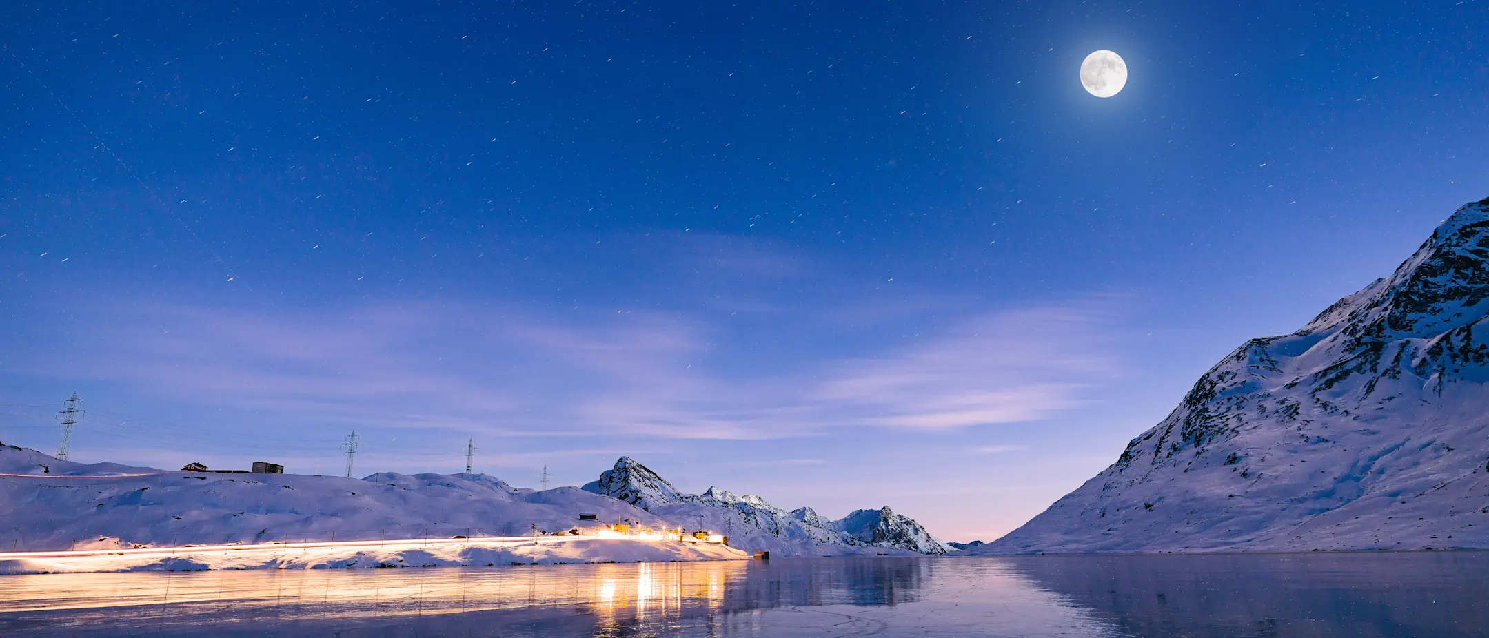 Vollmond am Lago Bianco, Bild in der Nacht, hell beleuchtete Bahnstrecke.