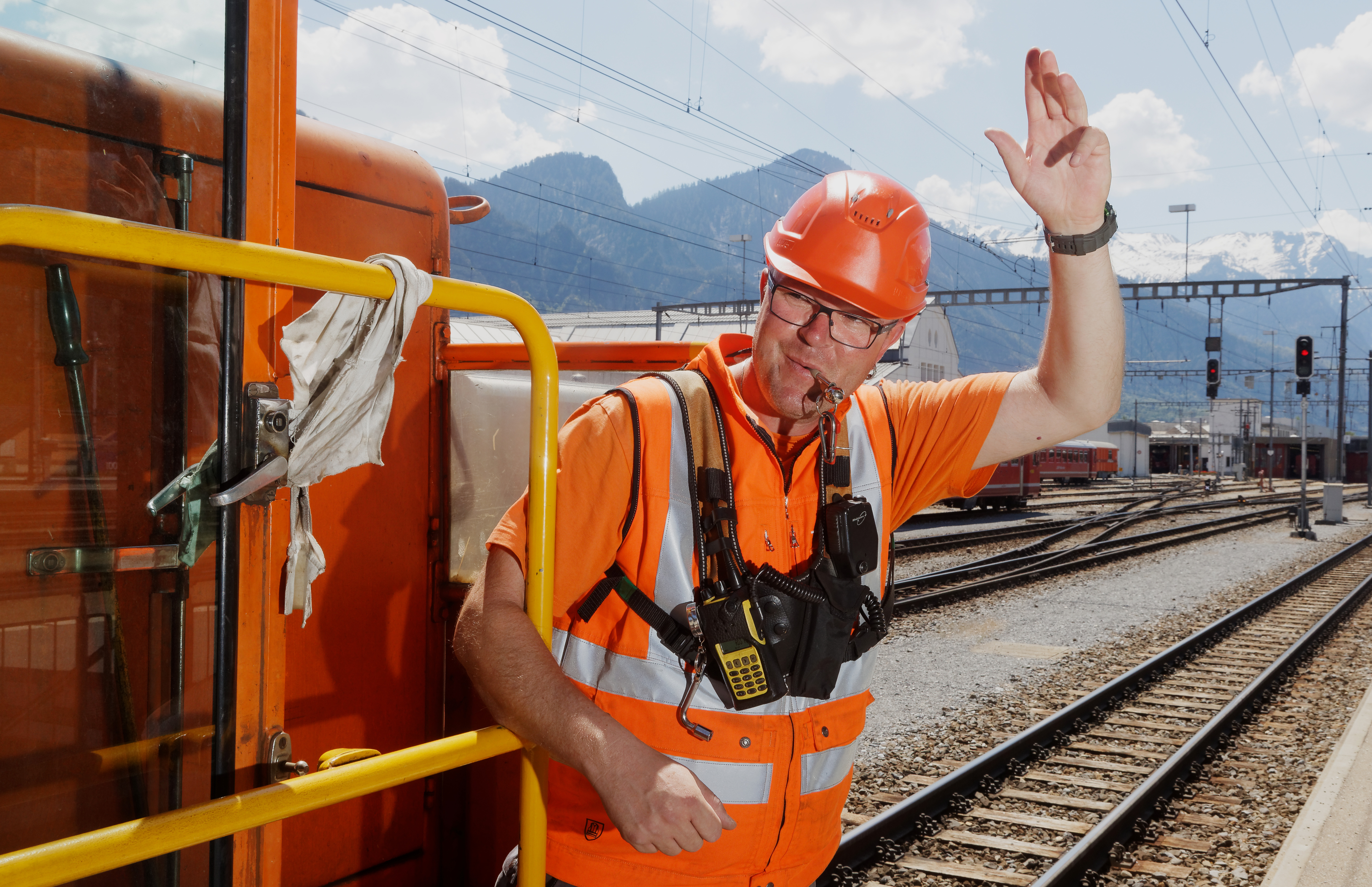 Un addetto allo smistamento fa cenno al macchinista di partire.