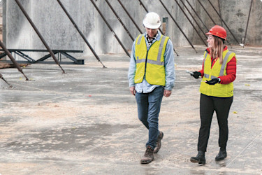 A man and a woman walk through a construction jobsite
