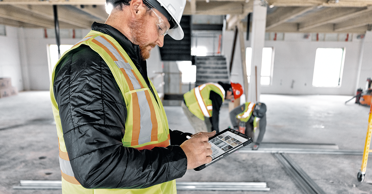 Construction worker using Fieldwire on a table on a jobsite