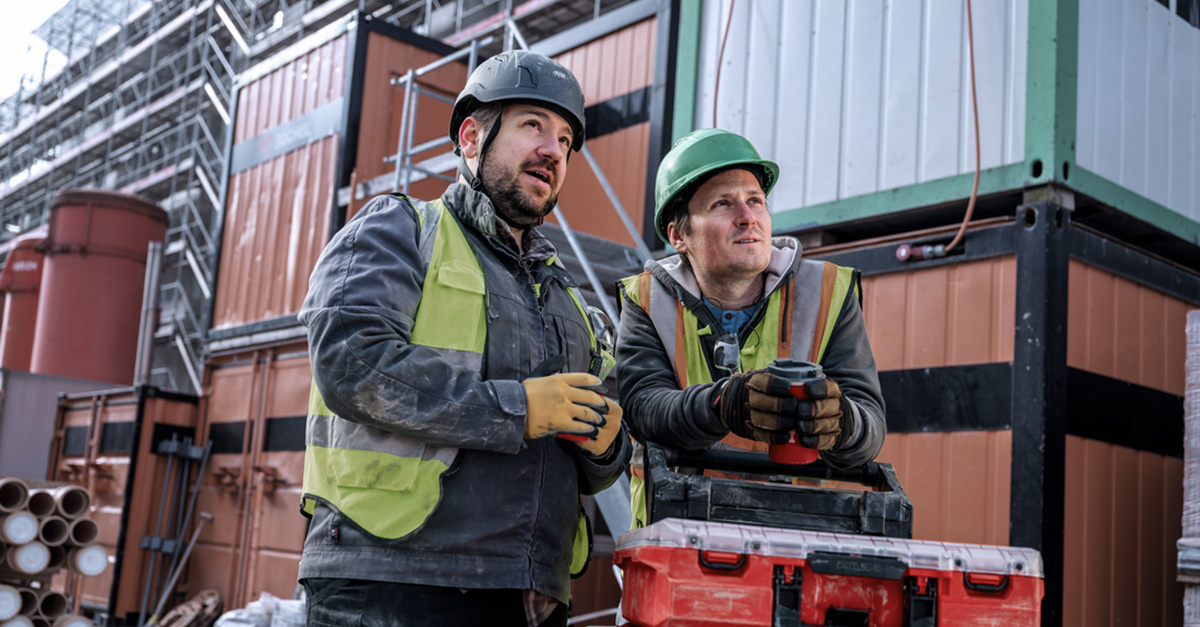 Two construction workers talking and having coffee on the jobsite.