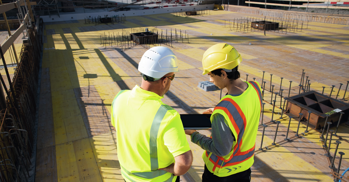 Two construction workers talking and holding a tablet on the jobsite