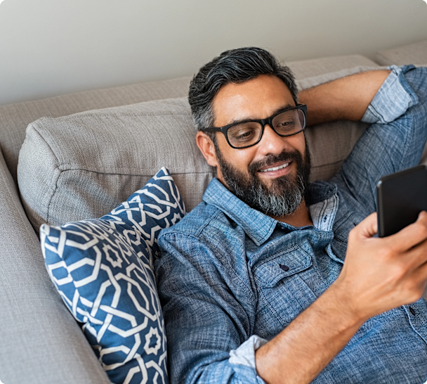 man on sofa using phone smiling
