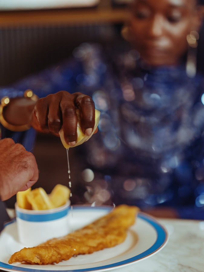 Squeezing a lemon on some deep fried cod