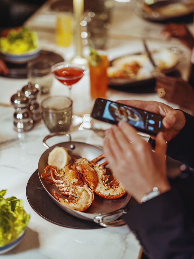 Man in suit taking a picture of his lobster mean