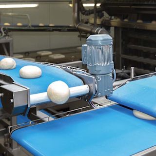 Industrial production line with dough pieces on blue conveyor belts in a bakery