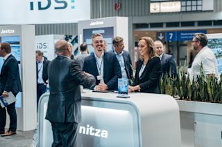 Janitza-Messestand auf einer Fachmesse mit Mitarbeitern, die mit Besuchern sprechen