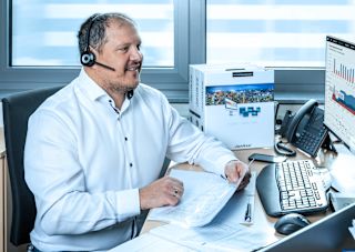 Technical support employee with a headset at a desk, providing customer assistance