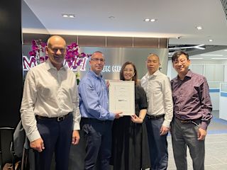 Janitza team on a business trip in Asia: Group photo with a certificate in a modern office.