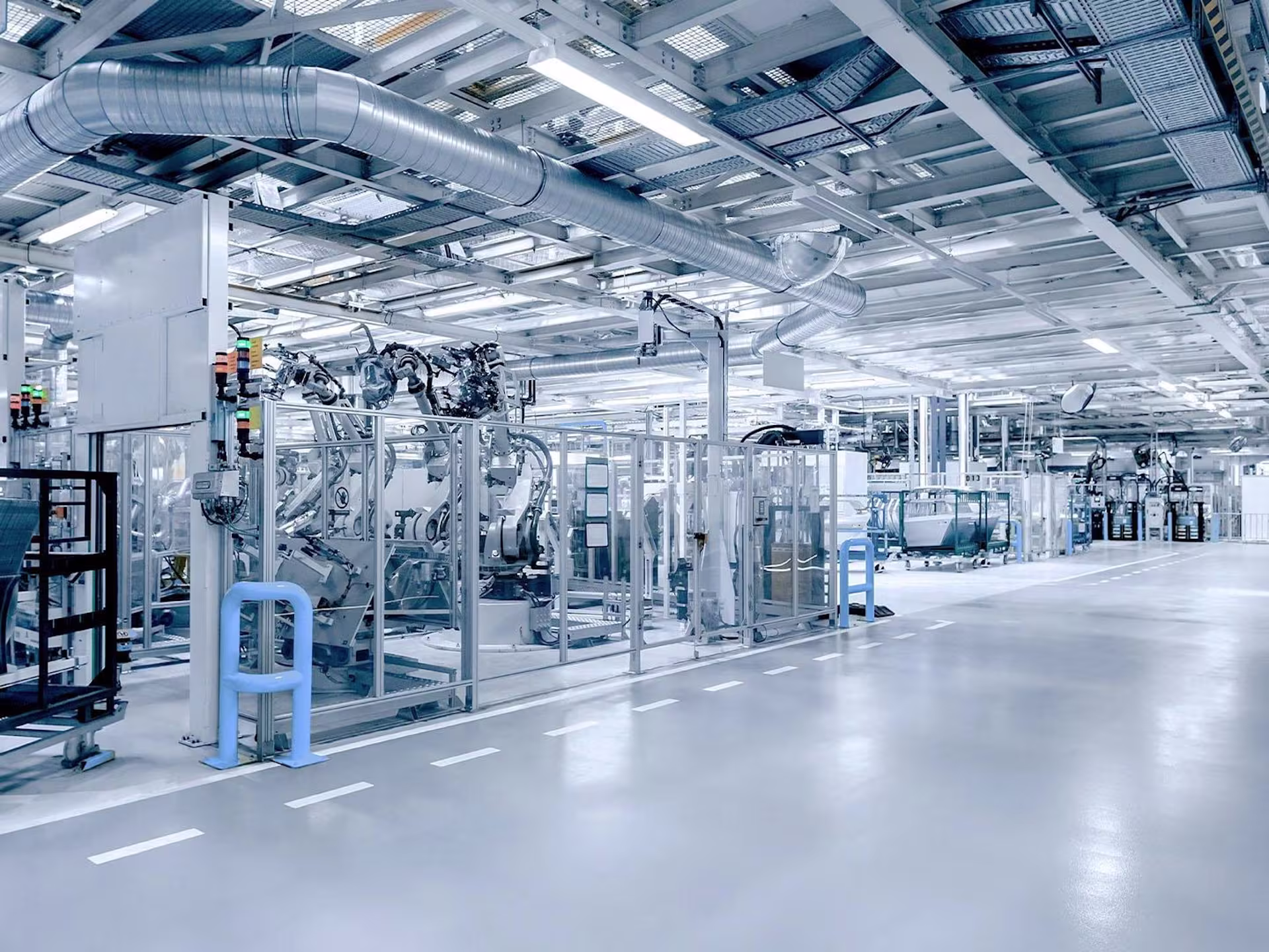 Large industrial shop floor with automated machines, robots and ventilation systems showing a modern production environment.