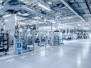 Large industrial shop floor with automated machines, robots and ventilation systems showing a modern production environment.