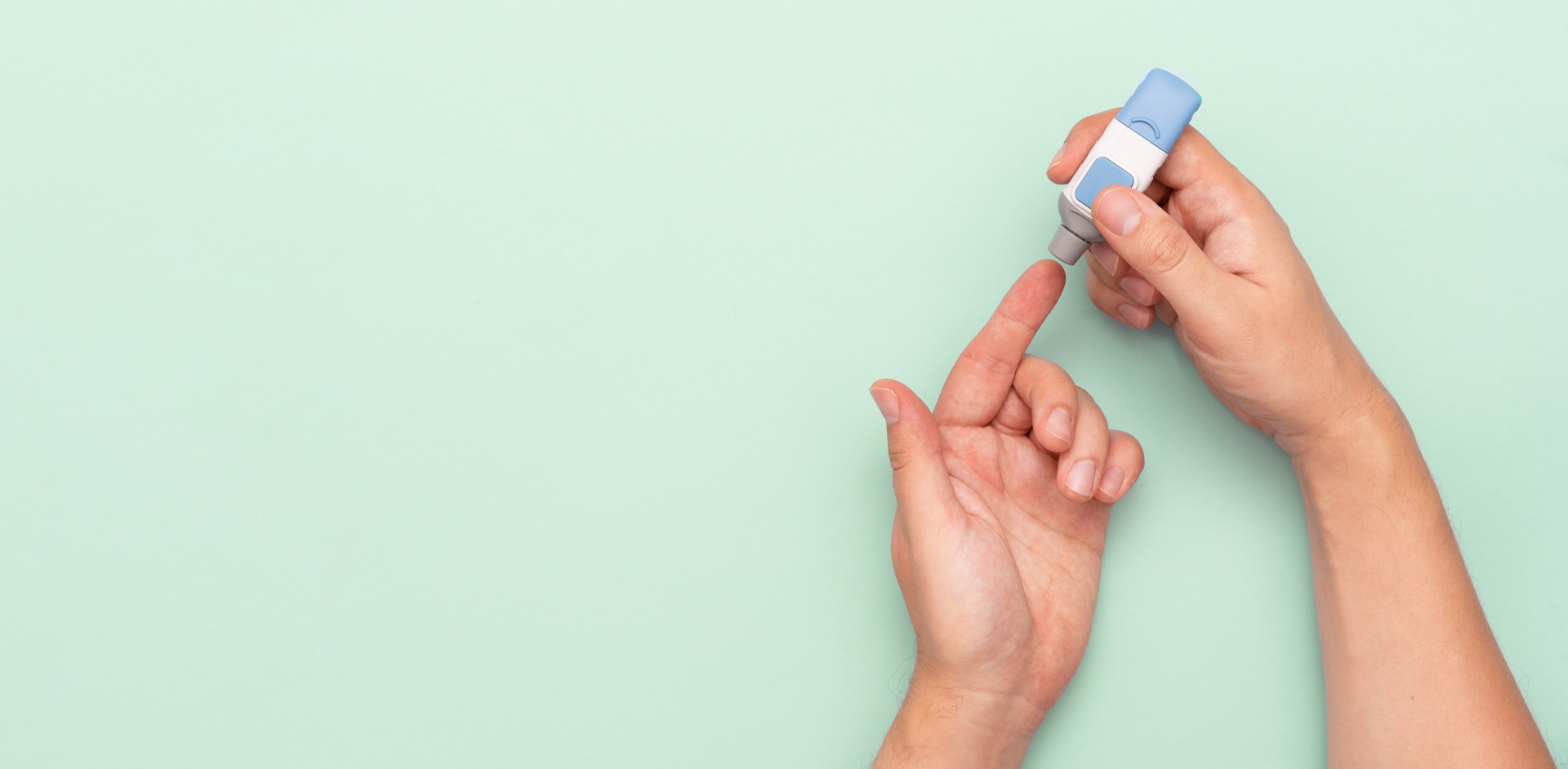 In the image, a lancet pen held in the right hand is about to be used to make a prick in the left hand's index finger.