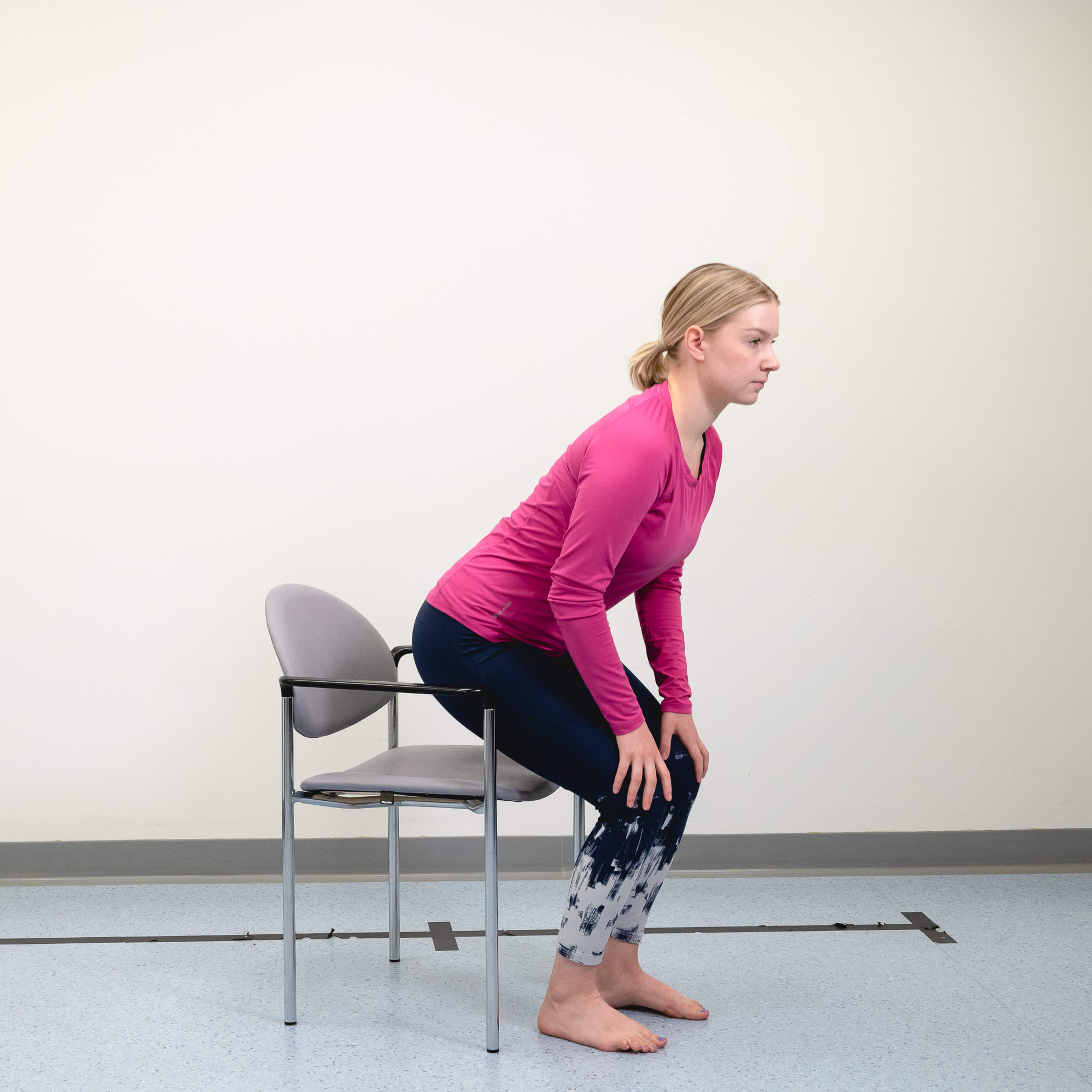 Nainen nousee tuolilta istumasta seisomaan