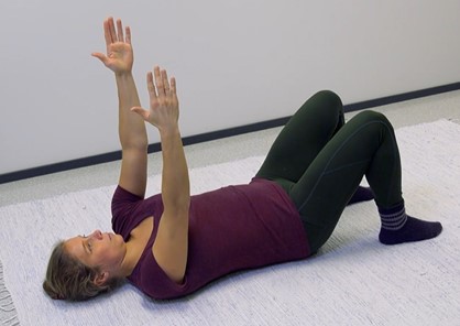 En kvinna ligger på rygg på golvet händerna uppåt.