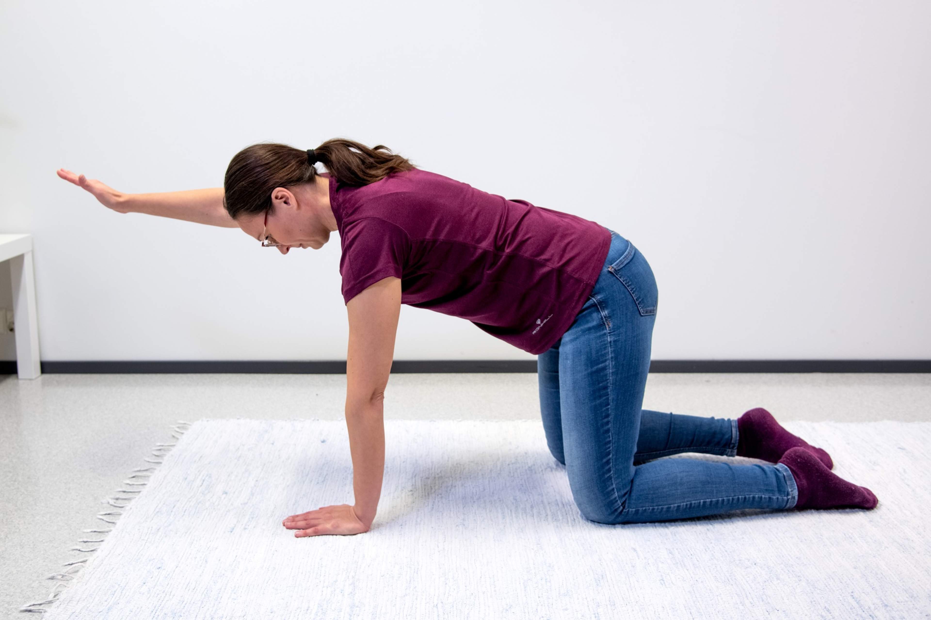 Nainen on lattialla konttausasennossa oikea käsi ojennettuna eteen.