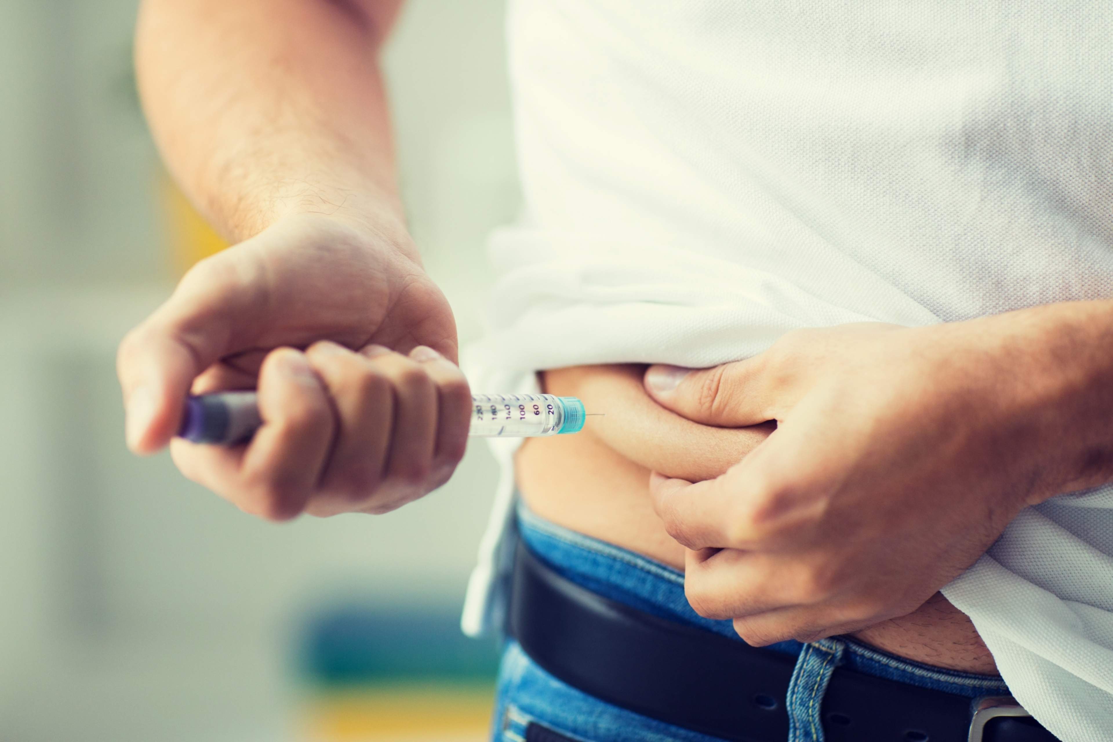 In the picture, insulin is being injected with an insulin pen into a skin fold lifted up from the stomach. The needle is inserted into the skin fold perpendicularly.