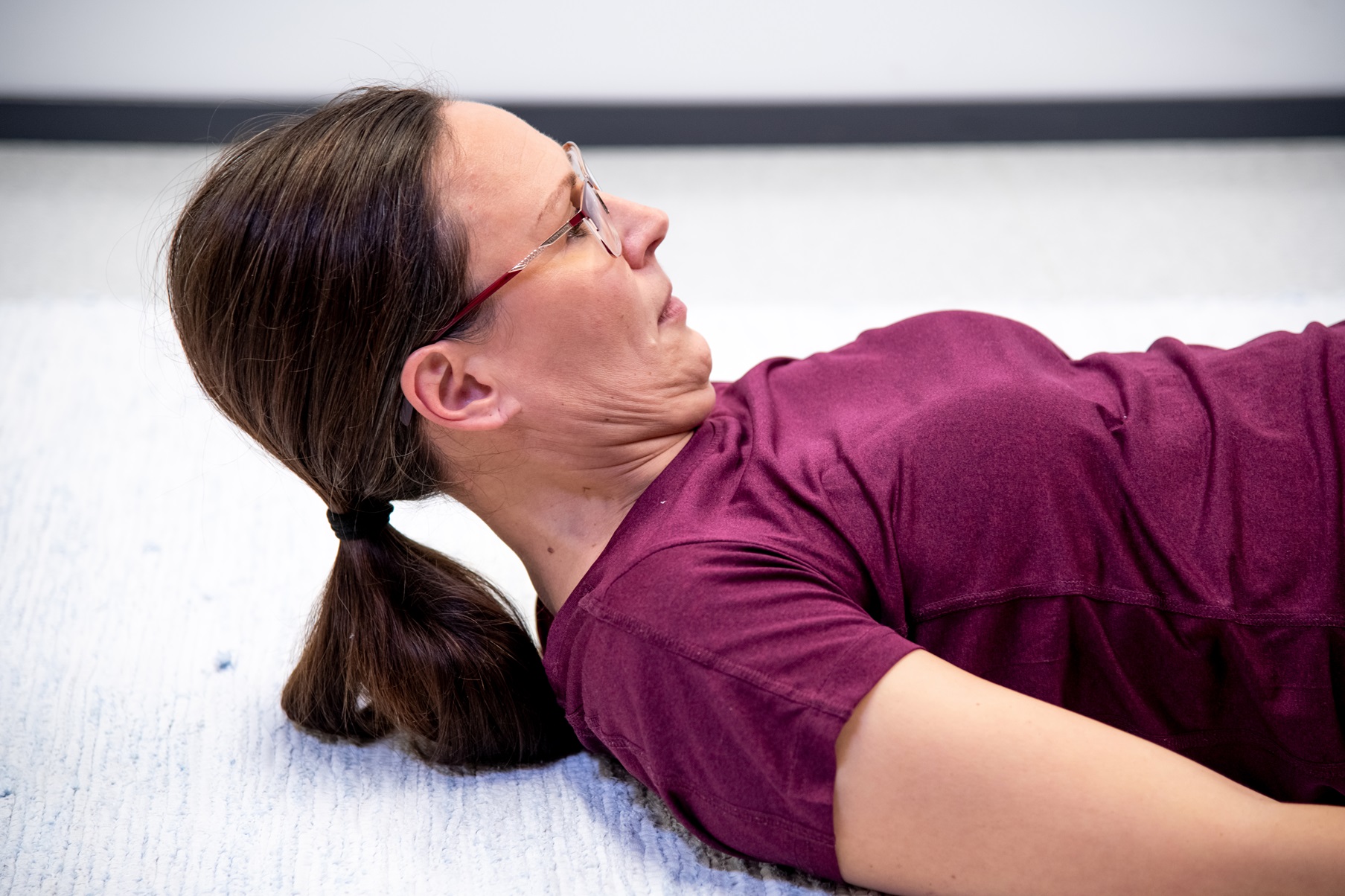 Kvinnan är liggande på rygg och huvudet är lyft från underlaget. 