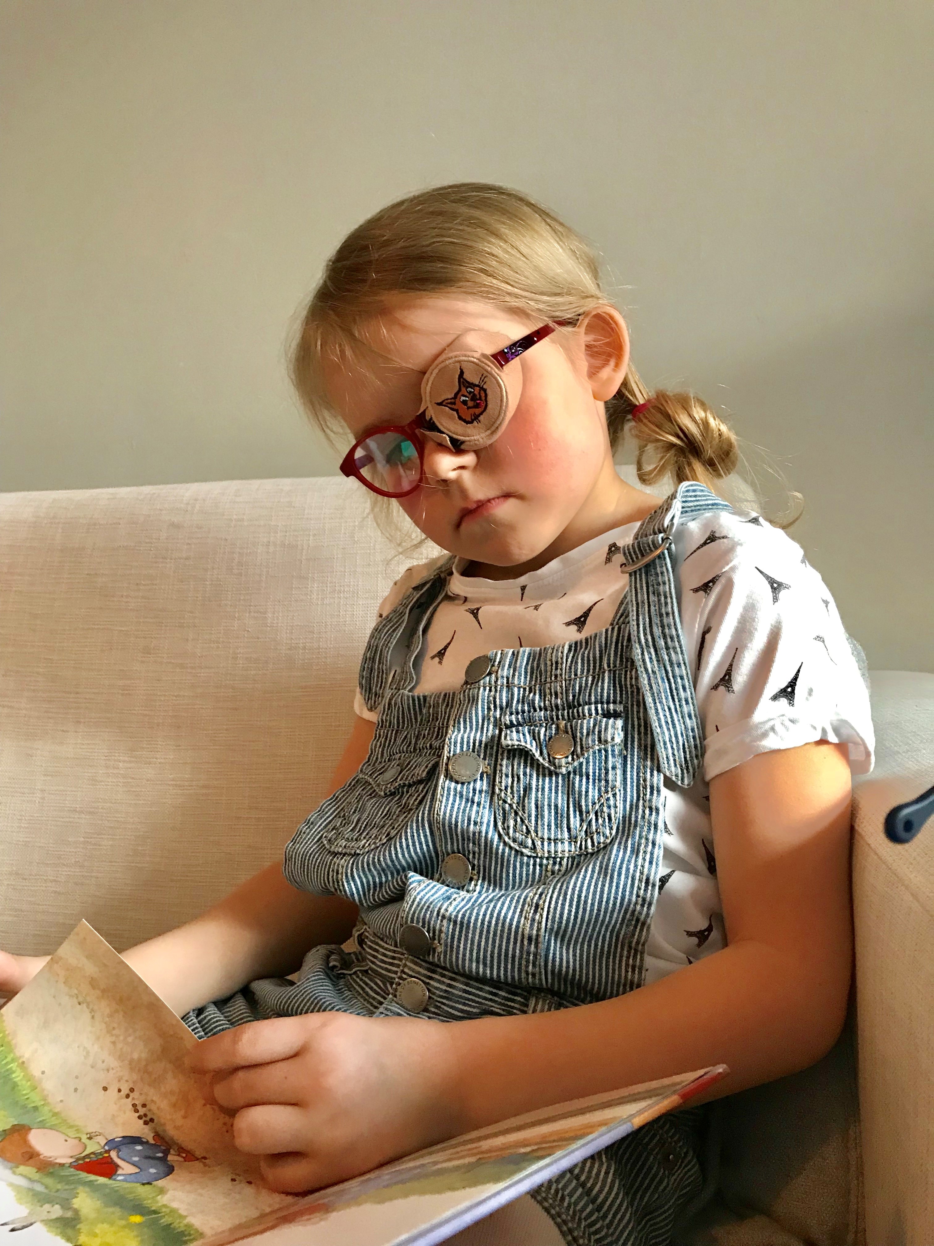 Lapsi lukee kirjaa. Toiminnallista heikkonäköisyyttä (amblyopia) voidaan hoitaa silmälaseilla ja joskus myös peittohoidolla.