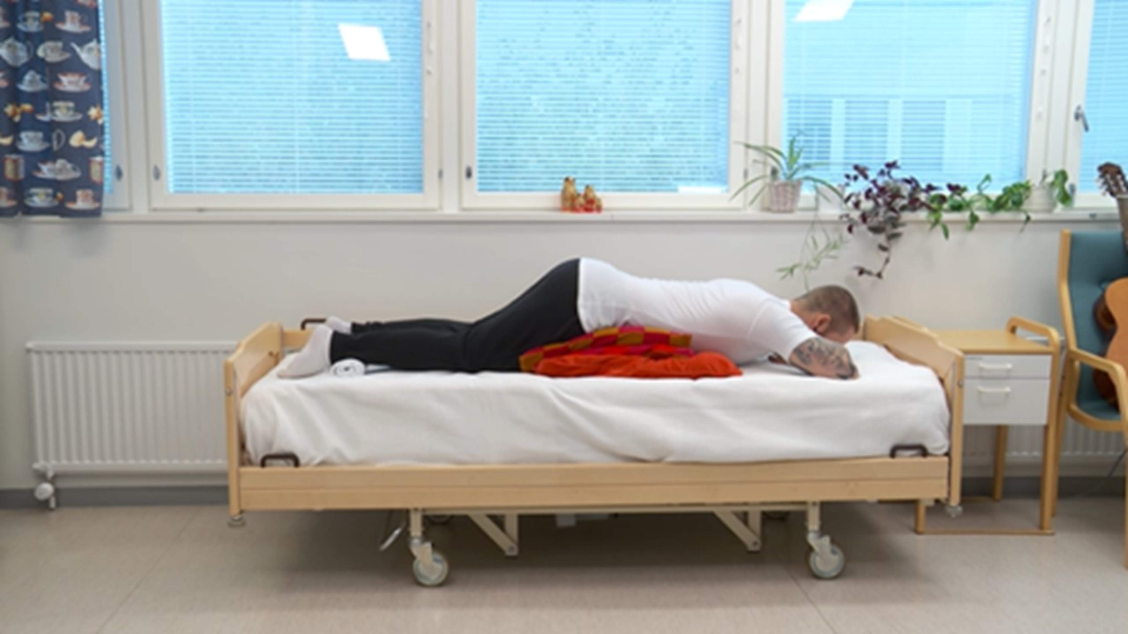 En man ligger på mage med kuddar under bäckenet.