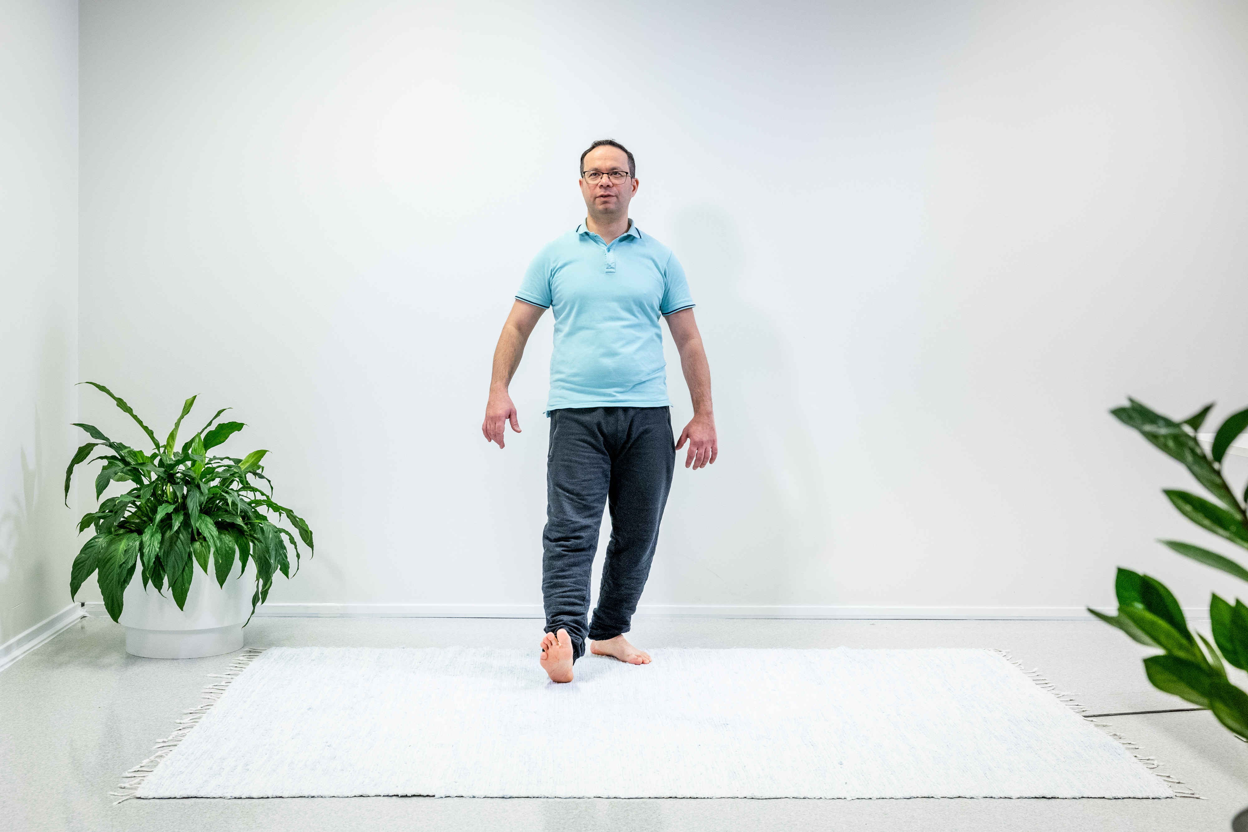 Mies on ottanut askeleen taaksepäin vasemmalla jalalla ja seisoo yhdellä jalalla. 