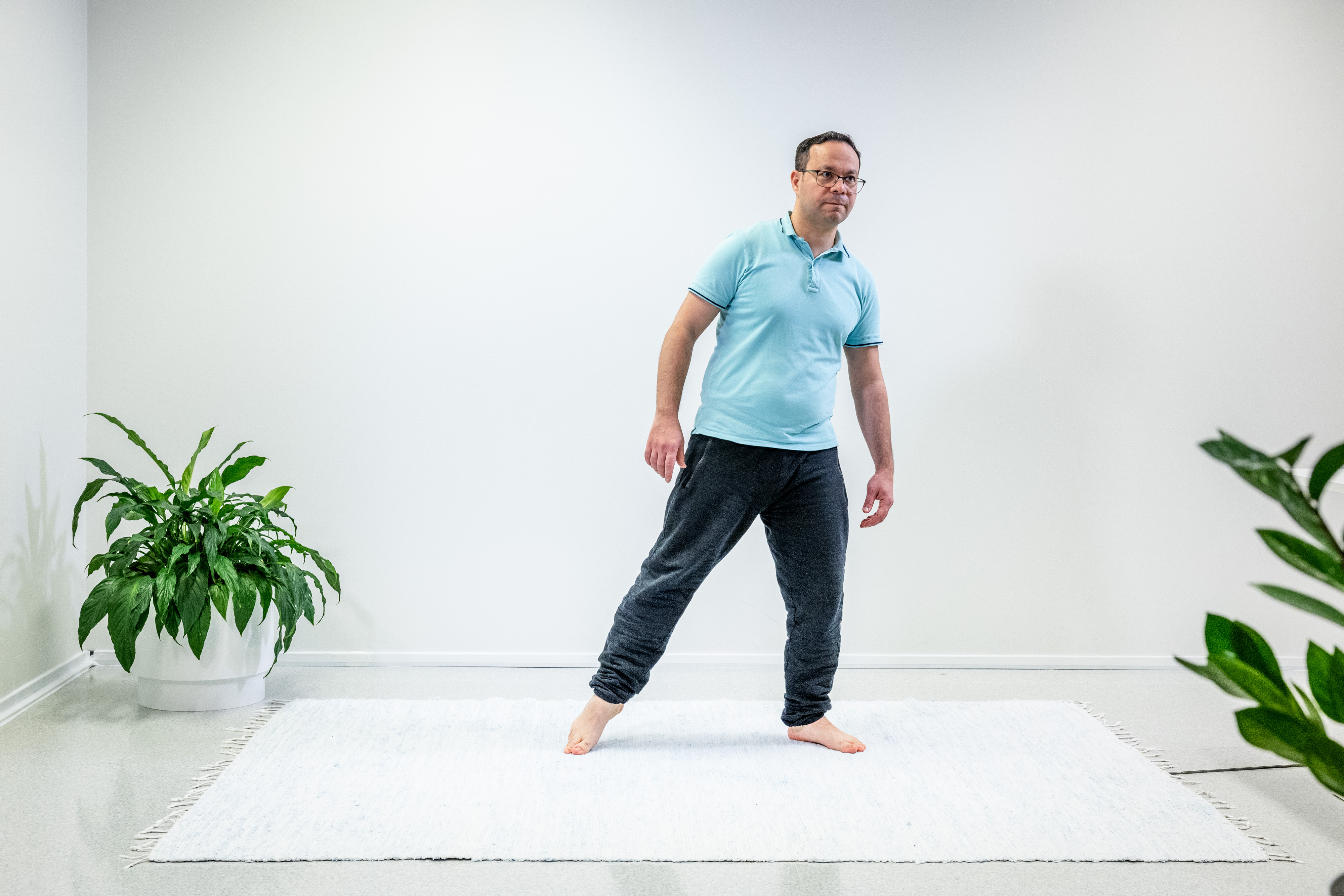 En man har tagit ett steg åt sidan med sitt vänstra ben och står på ett ben.