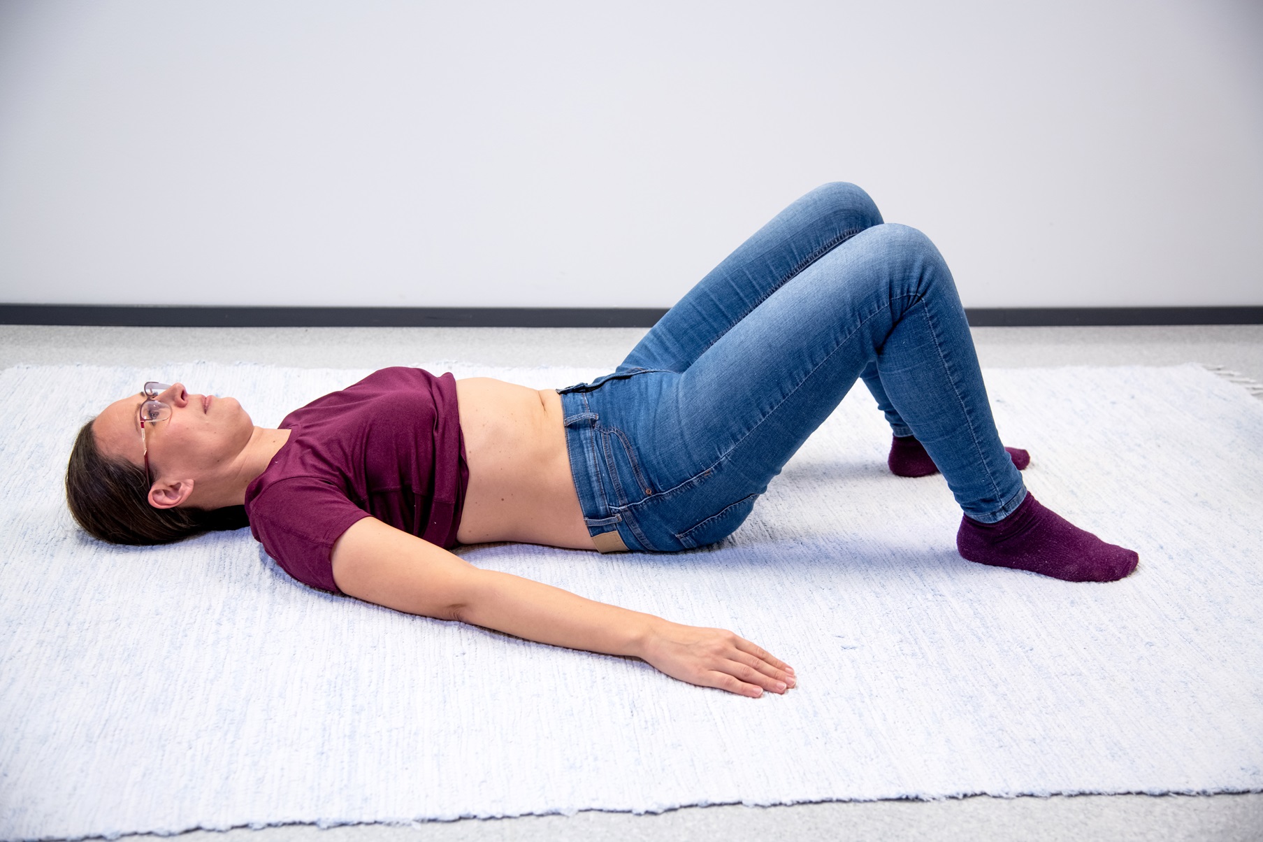 Kvinnan är liggande på rygg med knäna böjda och fötterna på underlaget händerna intill kroppen.