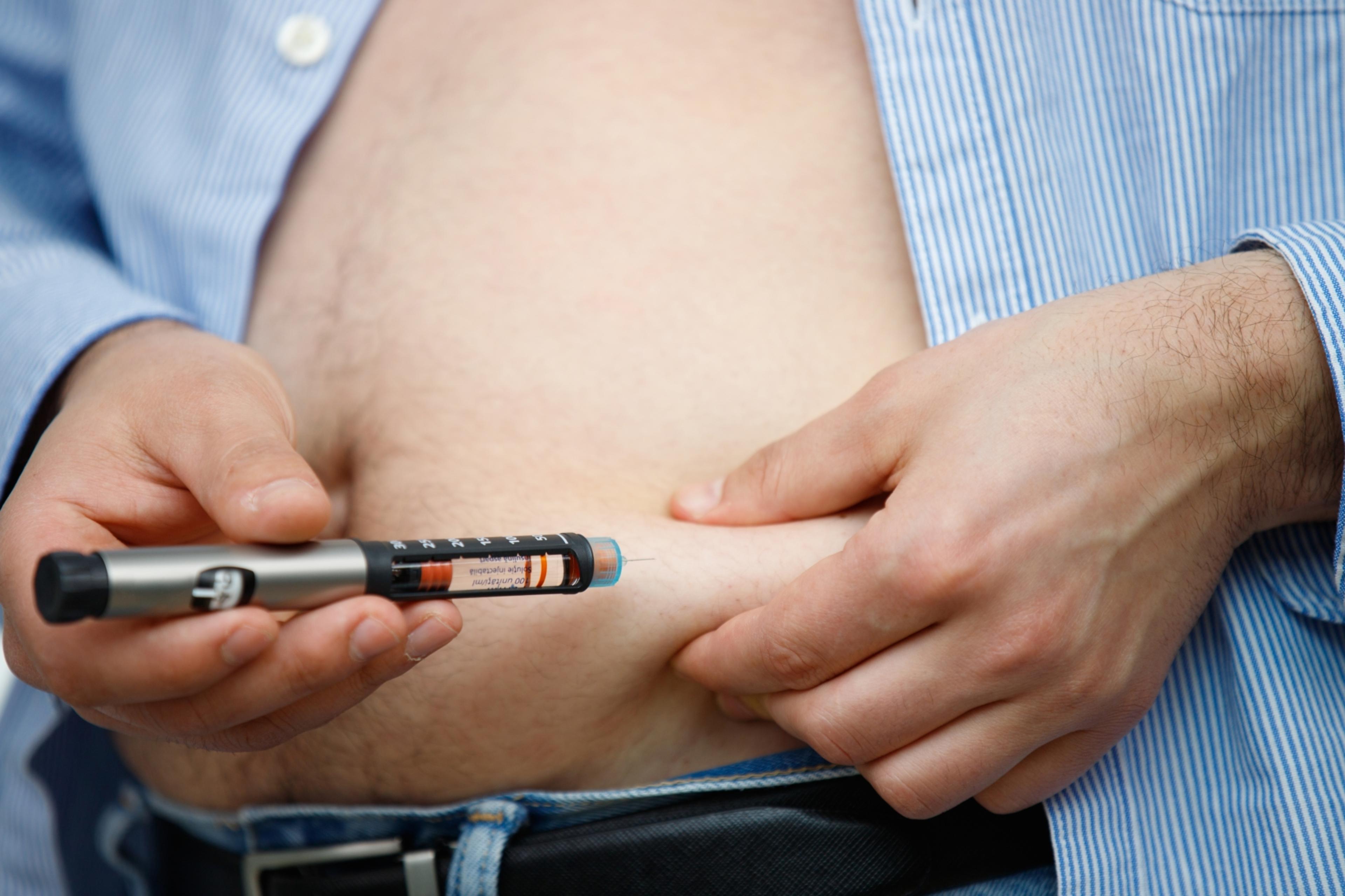 Administrering av snabbverkande insulin i buken på en bild. Med en hand lyfts en hudveck från magen, i vilken pennan trycks in vinkelrätt innan insulinet doseras genom att trycka på pennans ände.