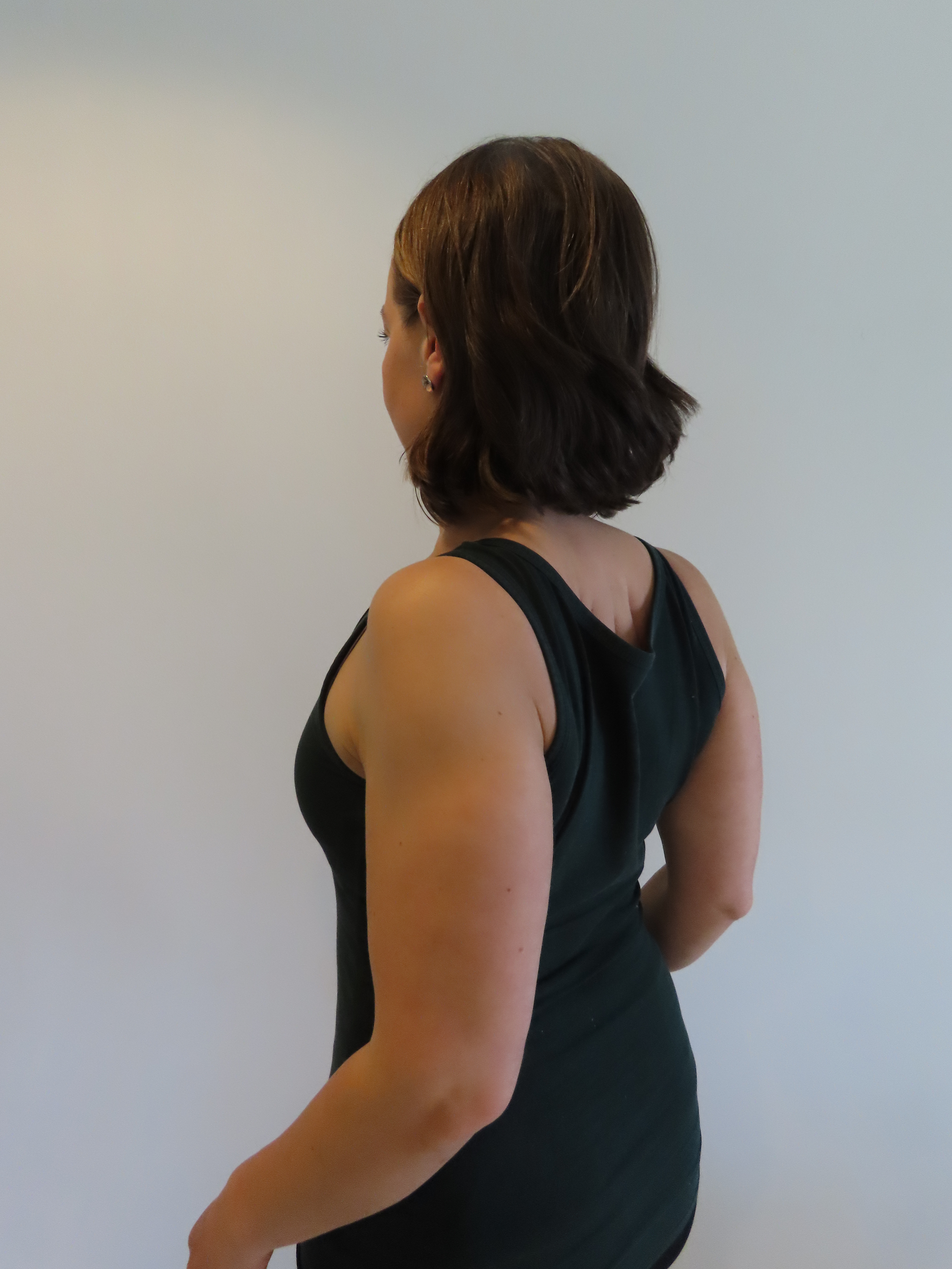 Kvinnan för skulderbladen ihop och nedåt.