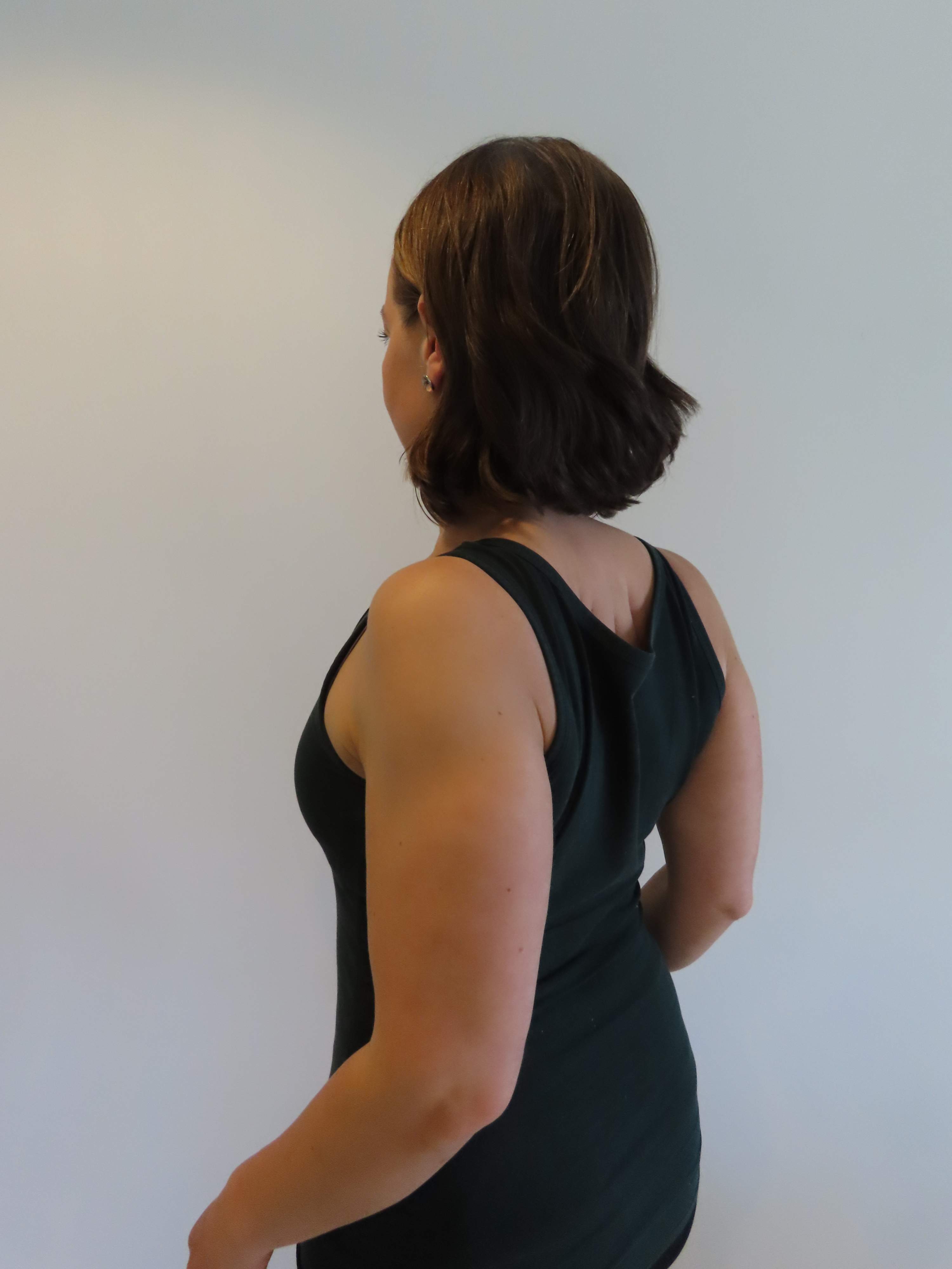 Kvinnan för skulderbladen ihop och nedåt.