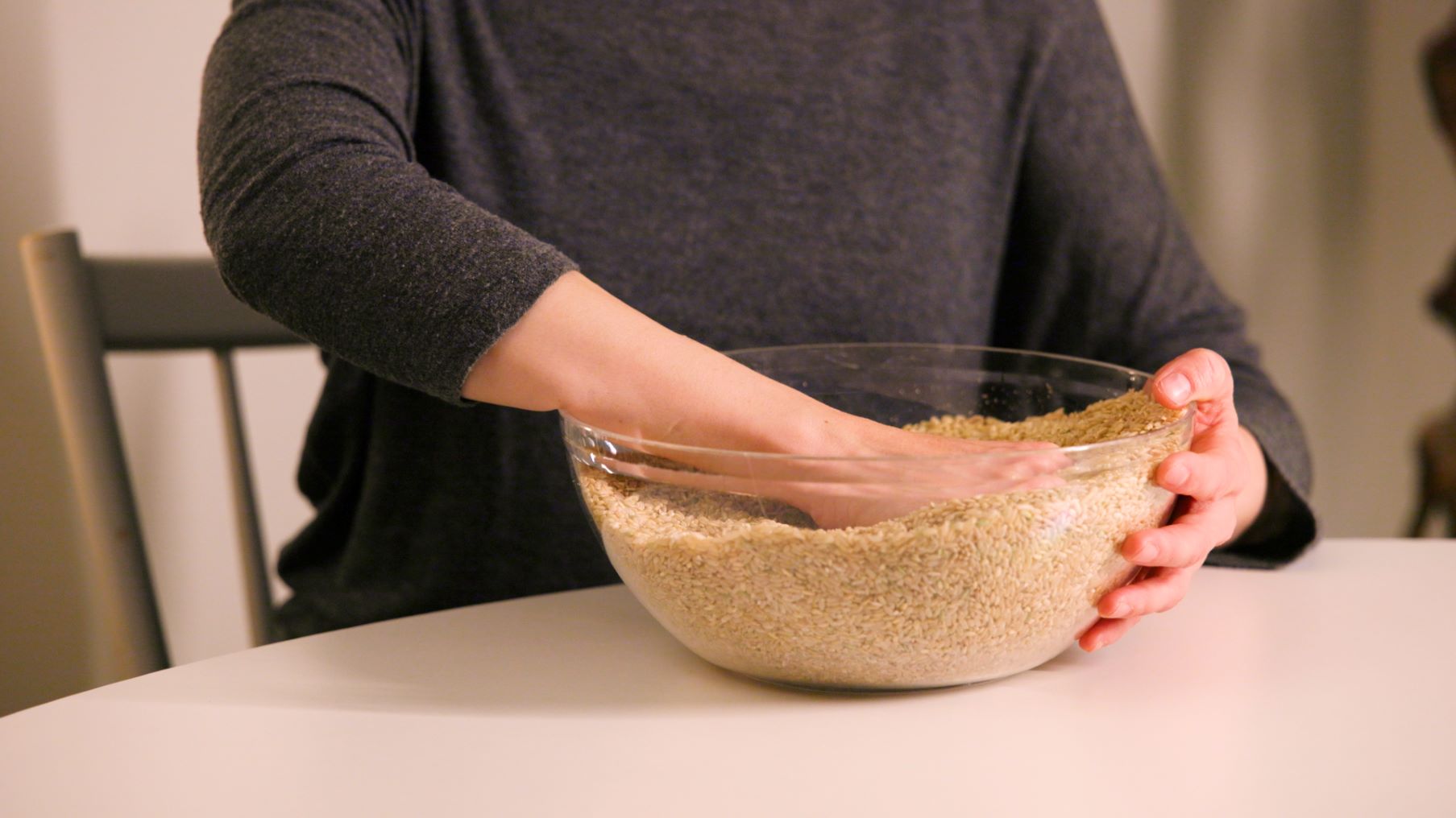 En persons hand är i en skål med ris. 