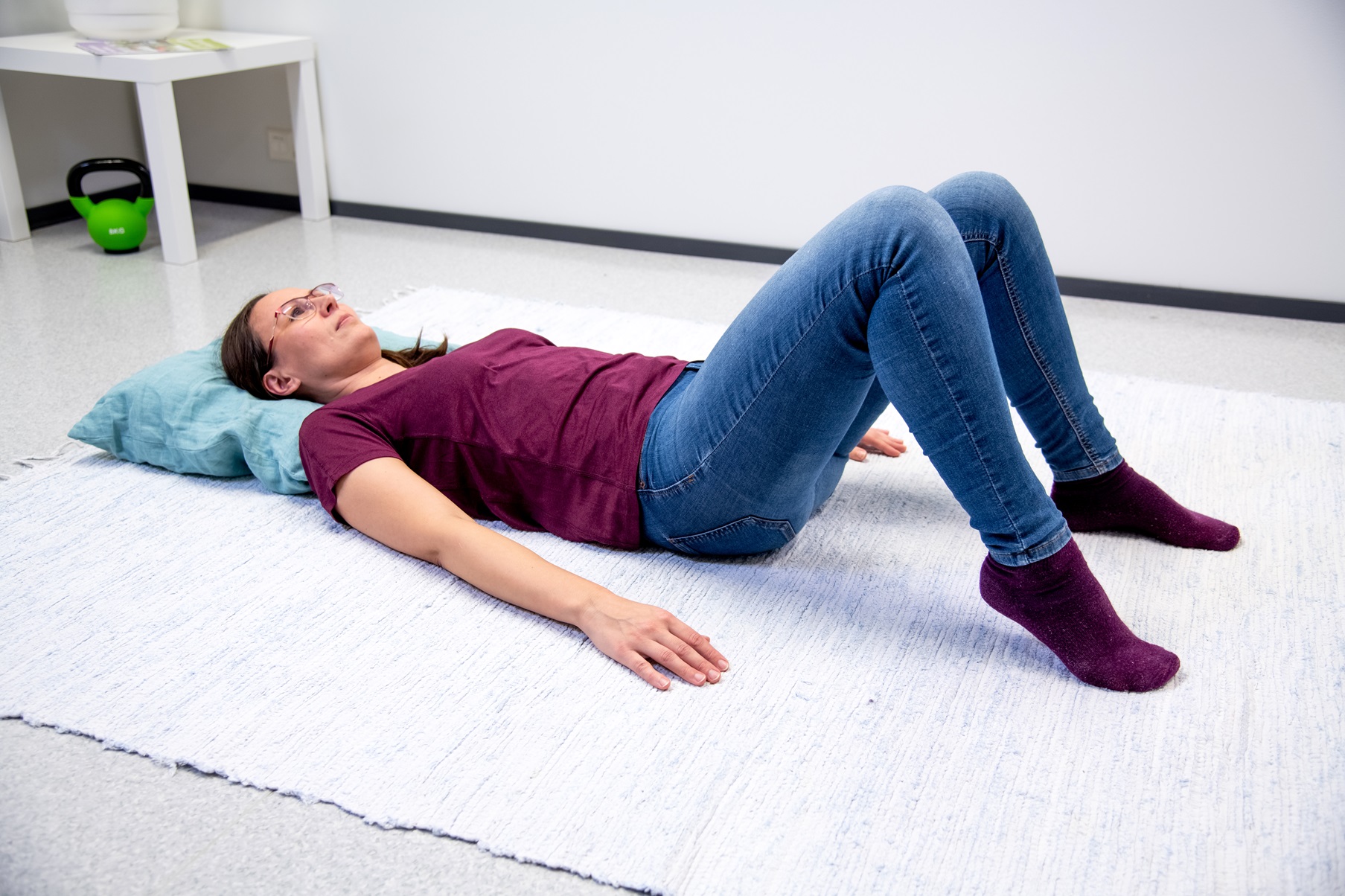 Kvinnan är liggande på rygg med knäna böjda och fötterna på underlaget. En hälen lyft från underlaget.