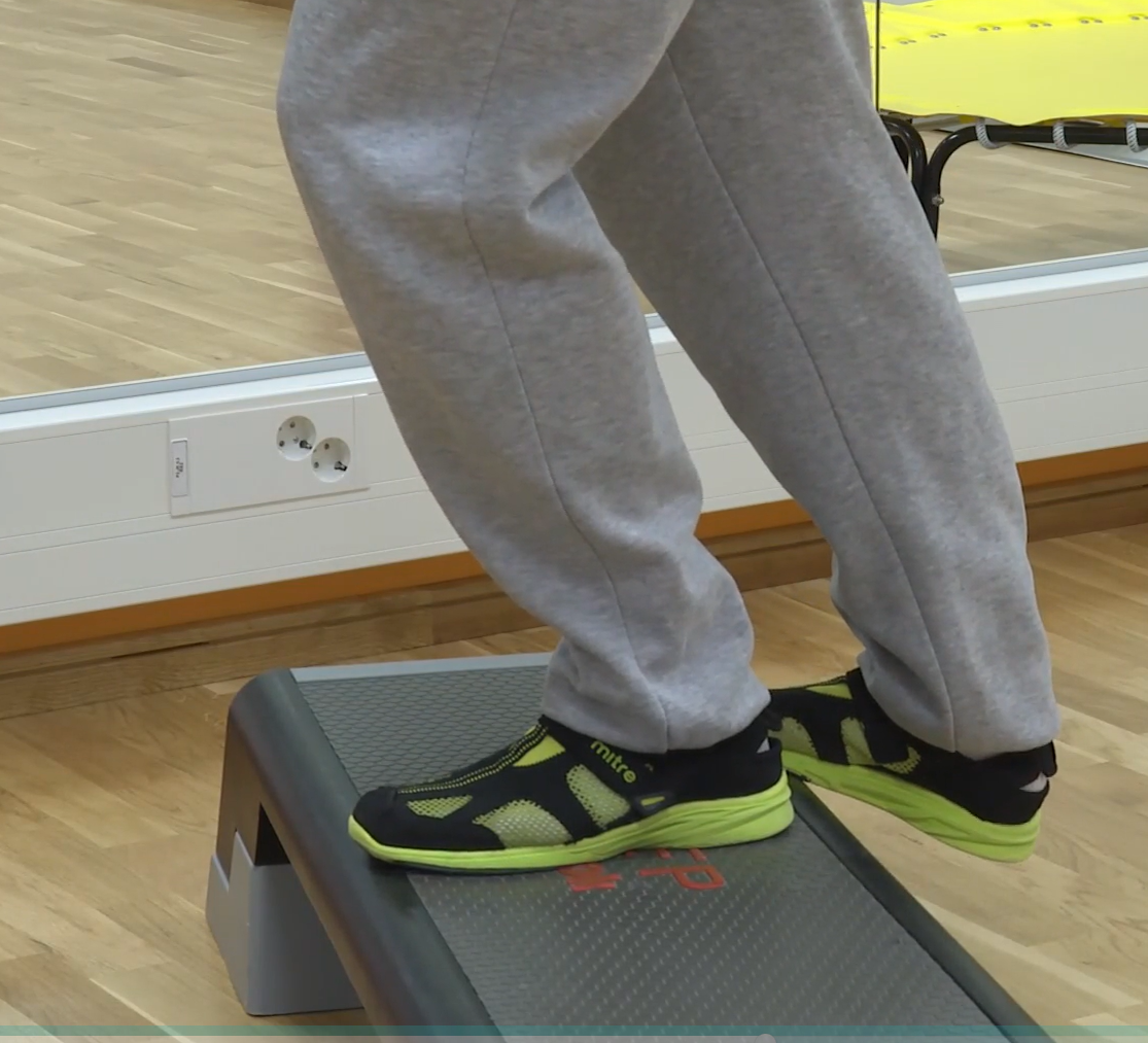 Mies seisoo portaalla vasemmalla jalalla, oikean jalan varpaat ovat portaalla ja kantapää portaan reunan yli. Vasen polvi on hieman koukussa ja oikea polvi suorana. 