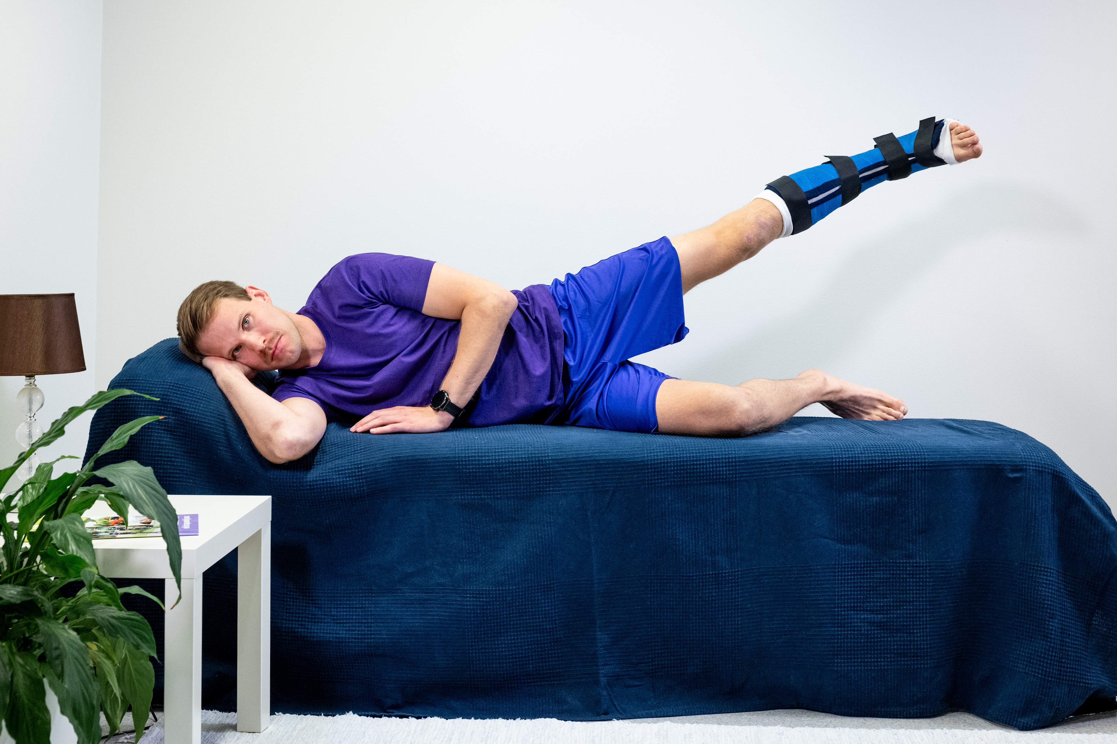 Mannen ligger på höger sida, det undre högra benet är böjt framför kroppen och det vänstra benet är gipsat. Mannen har lyft det vänstra benet uppåt åt sidan.