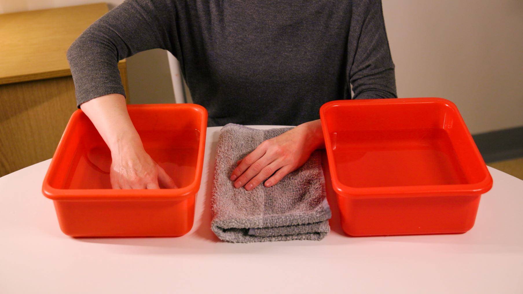 En persons hand är i ett vattenkärl och känner efter vattnets temperatur.