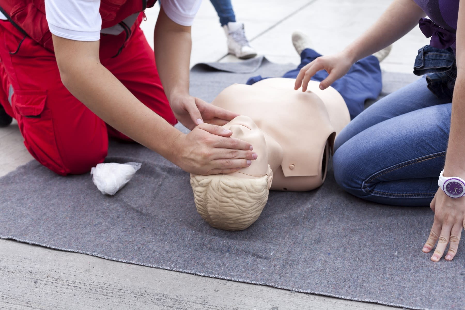A helper opens the airway of a CPR mannequin by slightly tilting its head back and lifting its chin