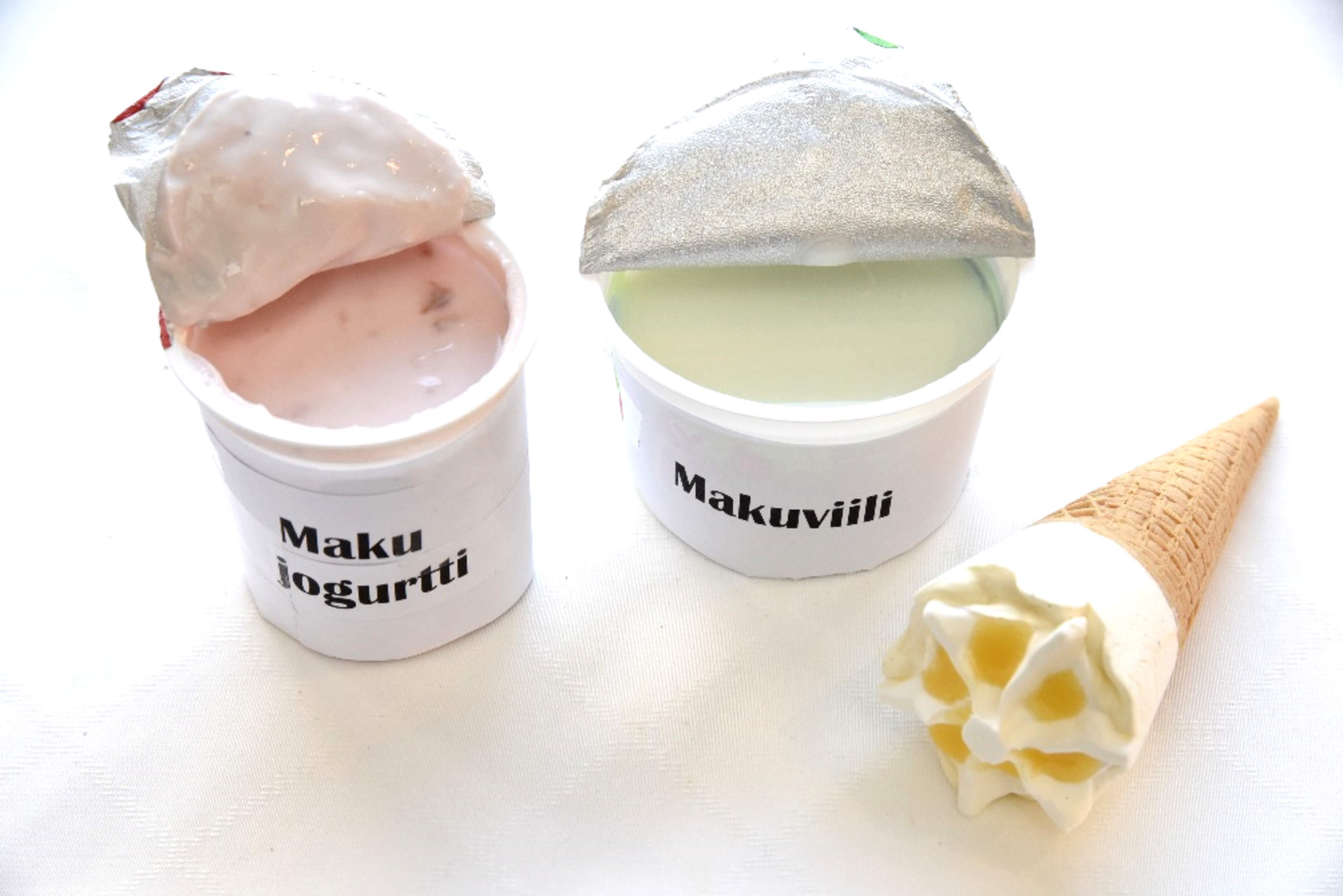 En burk smaksatt yoghurt, en burk smaksatt fil och en glasstrut.