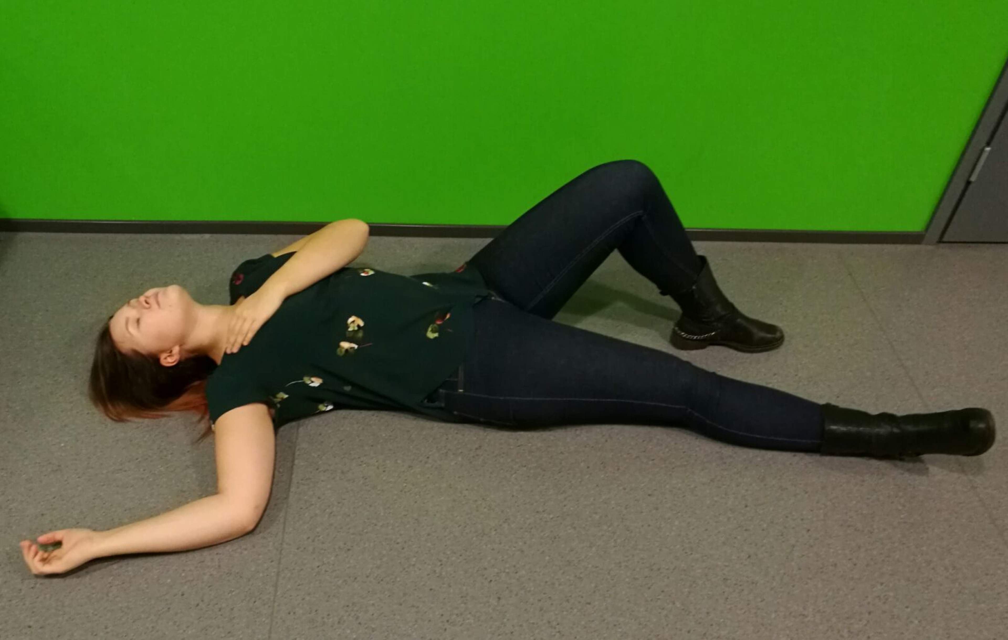 Before turning the unconscious person over, they are lying horizontally, with their back leg hooked and their arm on their chest.