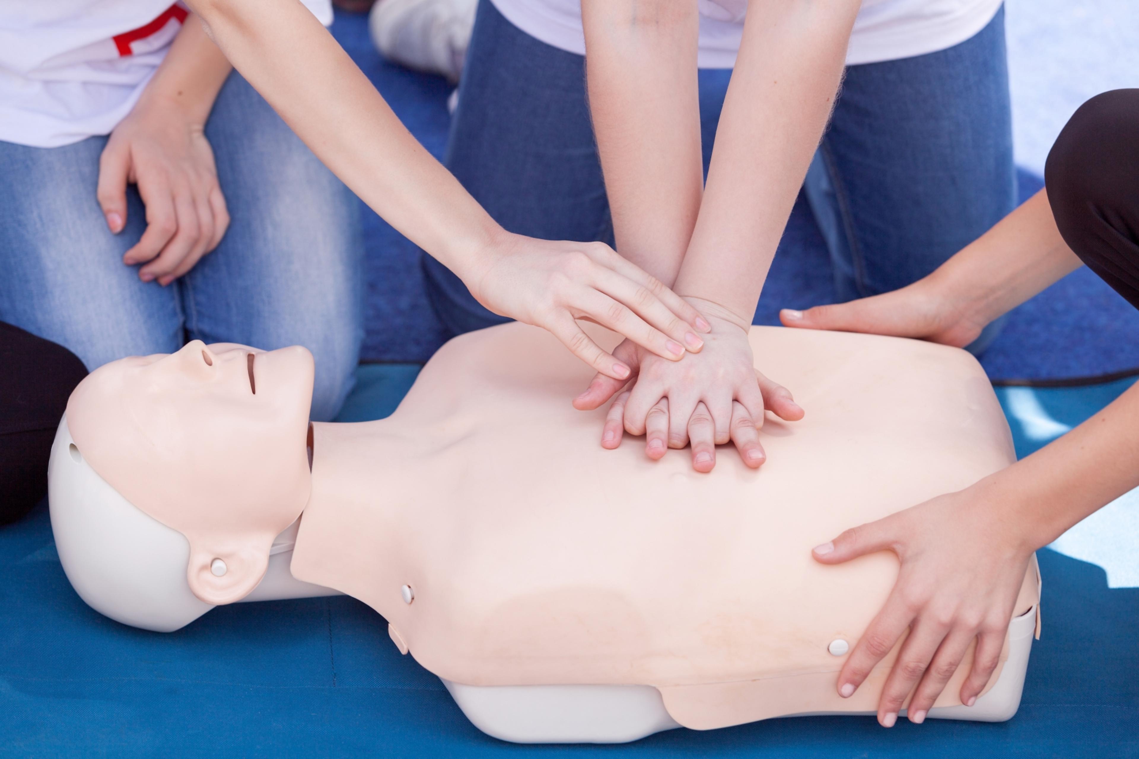 A helper places their hand in the correct position to apply pressure, in the middle of the CPR doll’s chest.