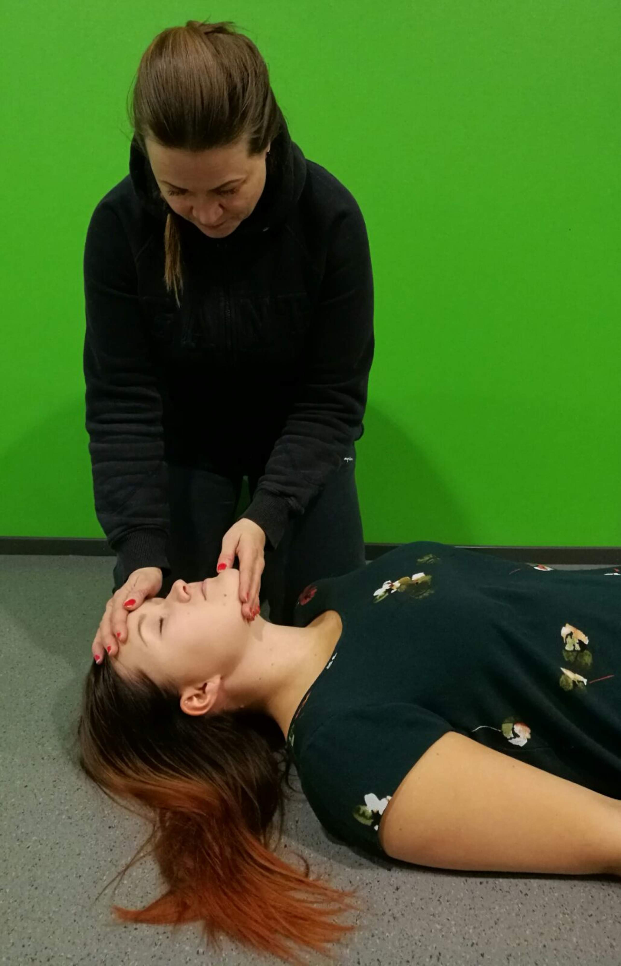 A helper opens the person’s airway by slightly tilting its head back and lifting its chin.