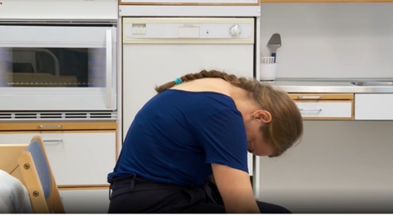 Nainen istuu ja pyöristää ylävartaloa eteenpäin.