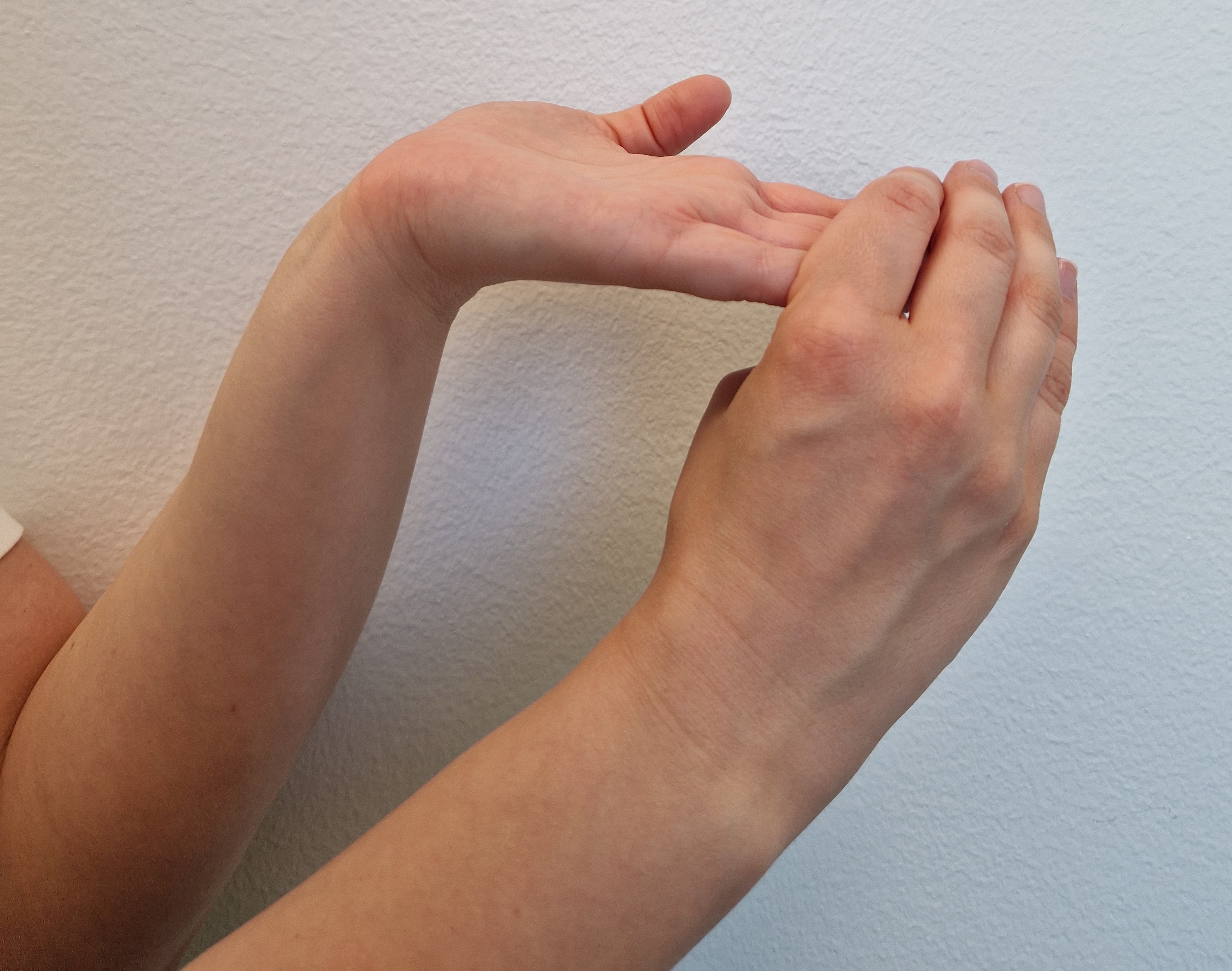 Fingrarna och handleden töjs till sträckning med hjälp av den andra handen.